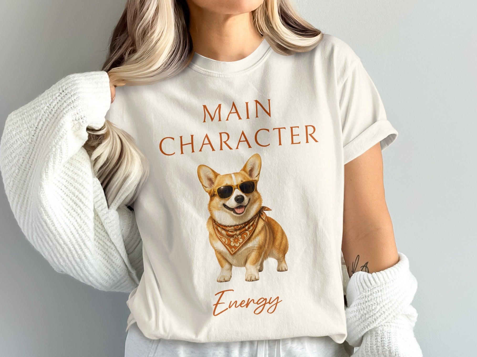 White t-shirt with "MAIN CHARACTER Energy" text and a cool corgi wearing sunglasses and a bandana.