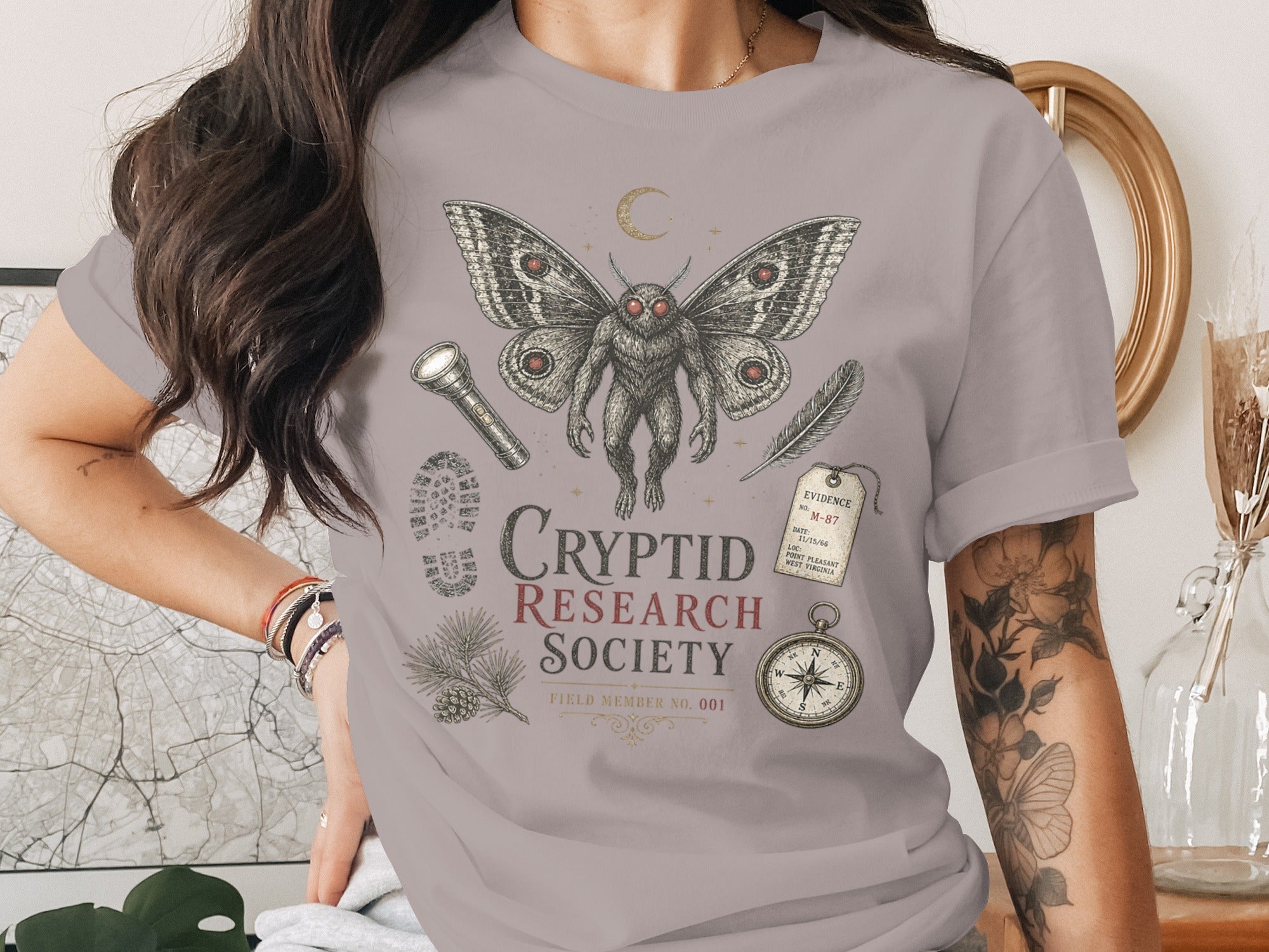 Mothman design with "Cryptid Research Society" text, evidence tag, and compass.
