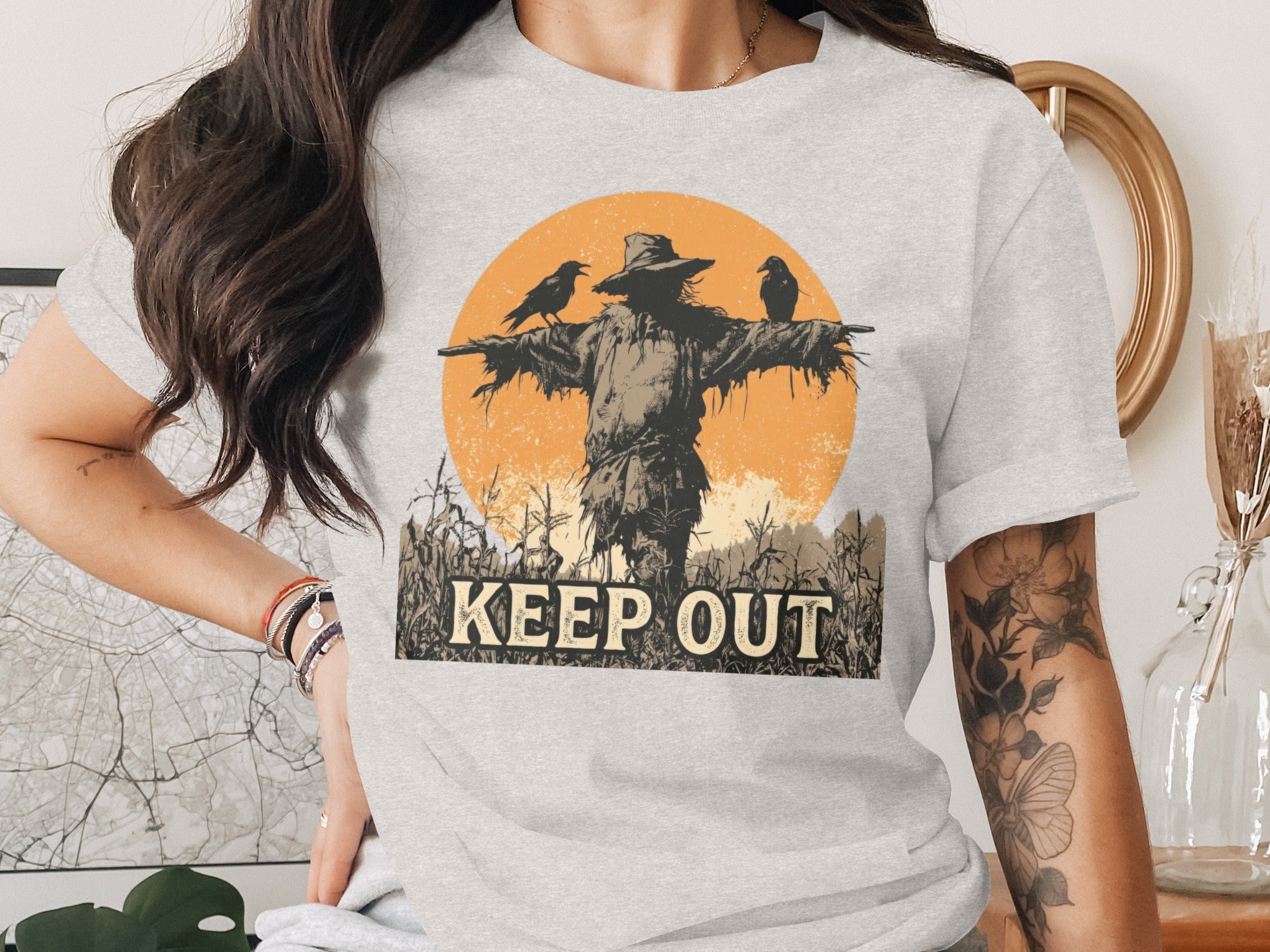 Scarecrow with crows and "KEEP OUT" text on a light gray t-shirt.