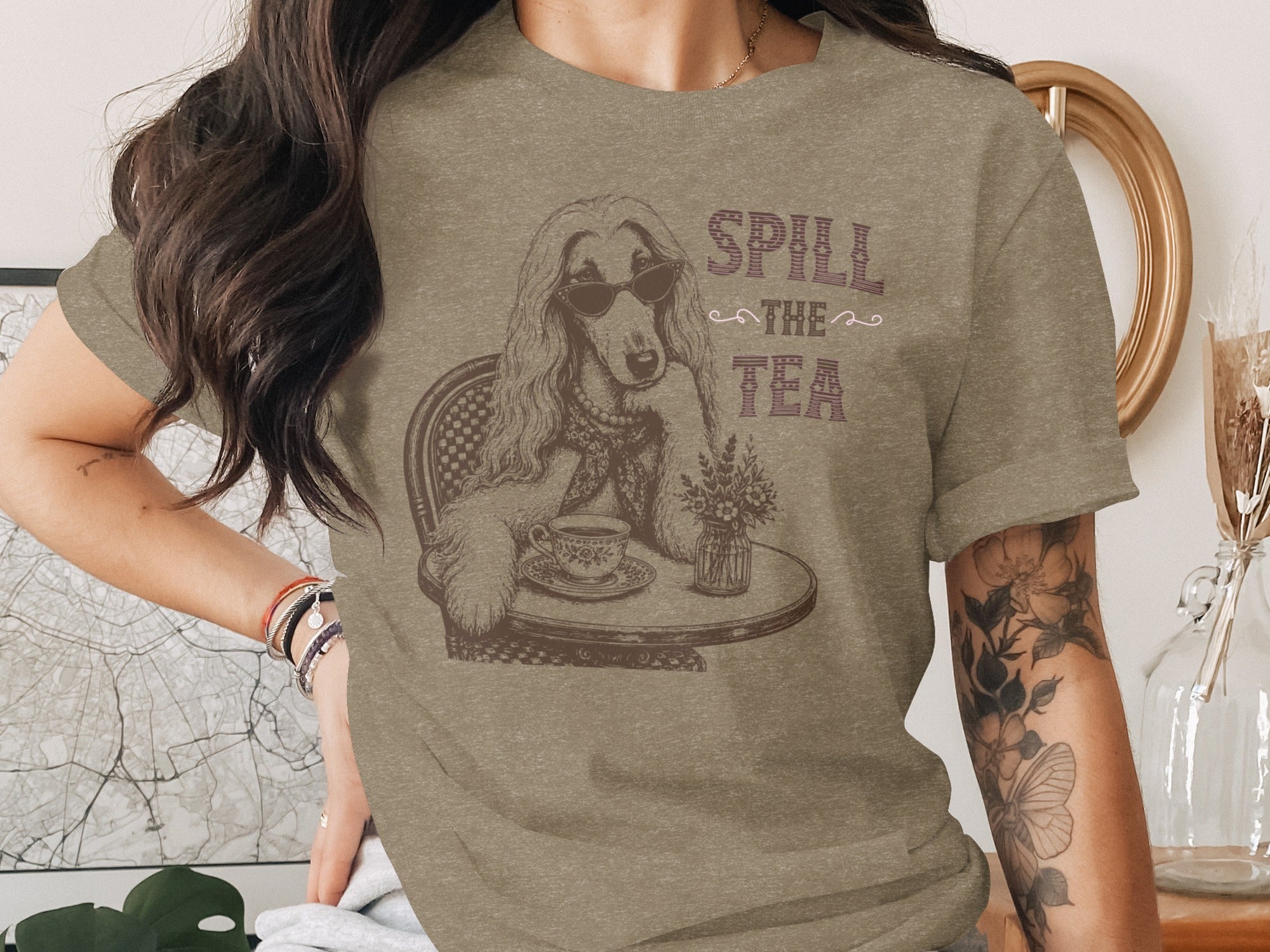 T-shirt graphic of a dog with sunglasses, sitting at a table drinking tea, with "Spill the Tea" text.
