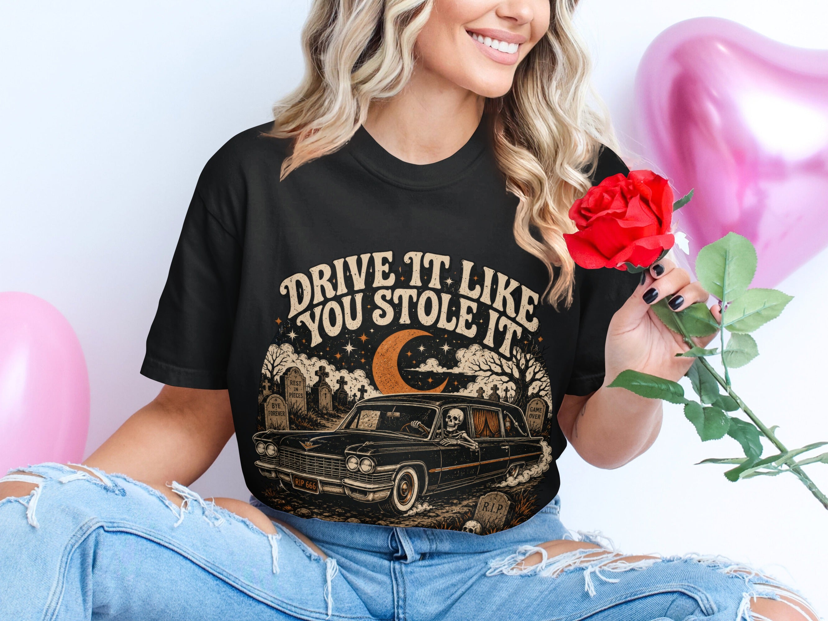 Black t-shirt graphic with skeleton driving car and text "DRIVE IT LIKE YOU STOLE IT".