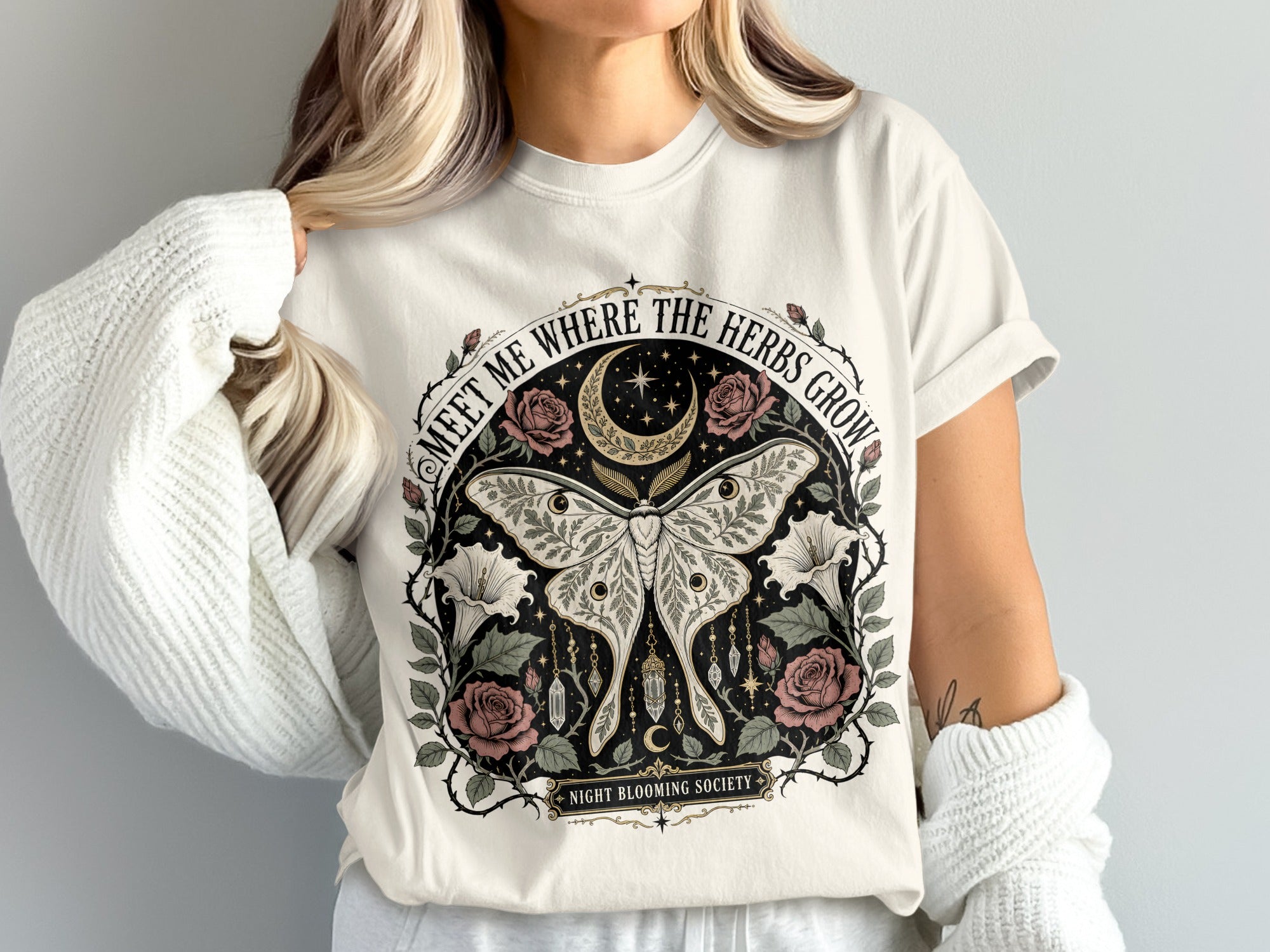 White t-shirt with a circular design featuring a moth, moon, roses, and text "NIGHT BLOOMING SOCIETY".