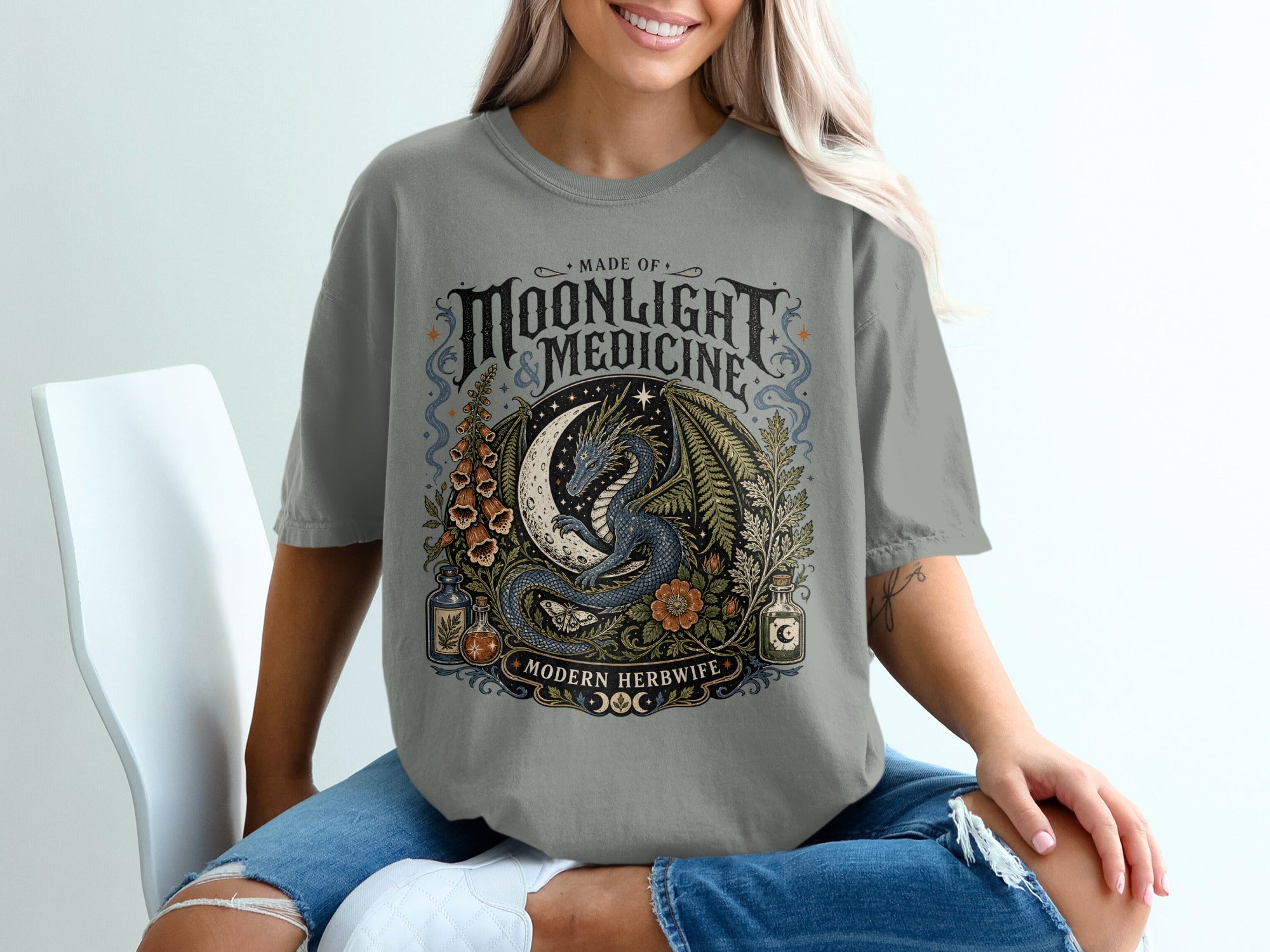 Graphic tee with a dragon, moon, plants, and text "Made of Moonlight & Medicine Modern Herbwife."