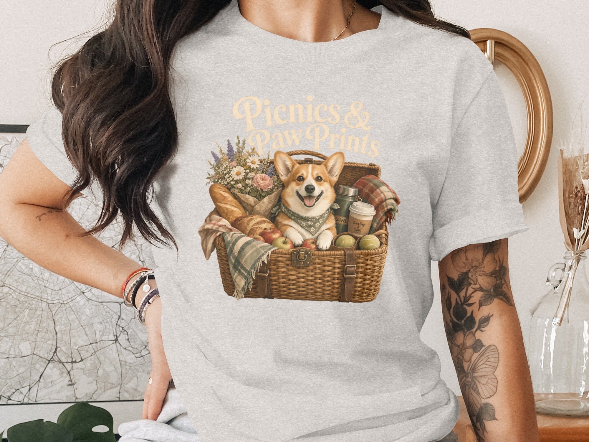 Gray t-shirt graphic with text "Picnics & Paw Prints" and a corgi in a picnic basket.