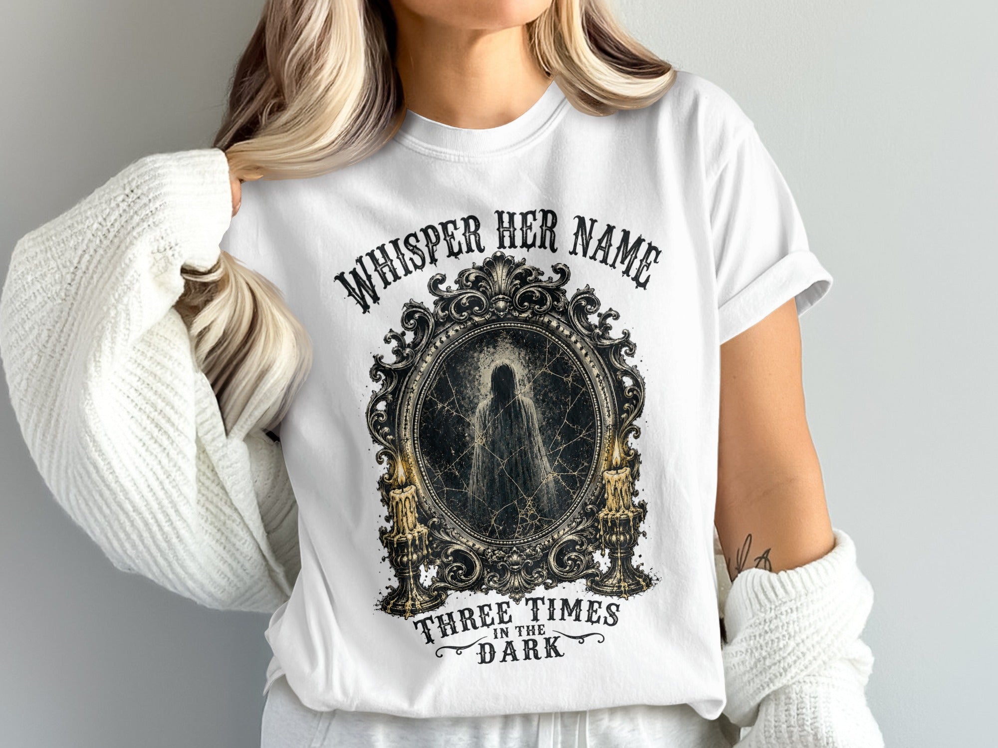 White t-shirt with "Whisper Her Name Three Times in the Dark" text and ghost image.