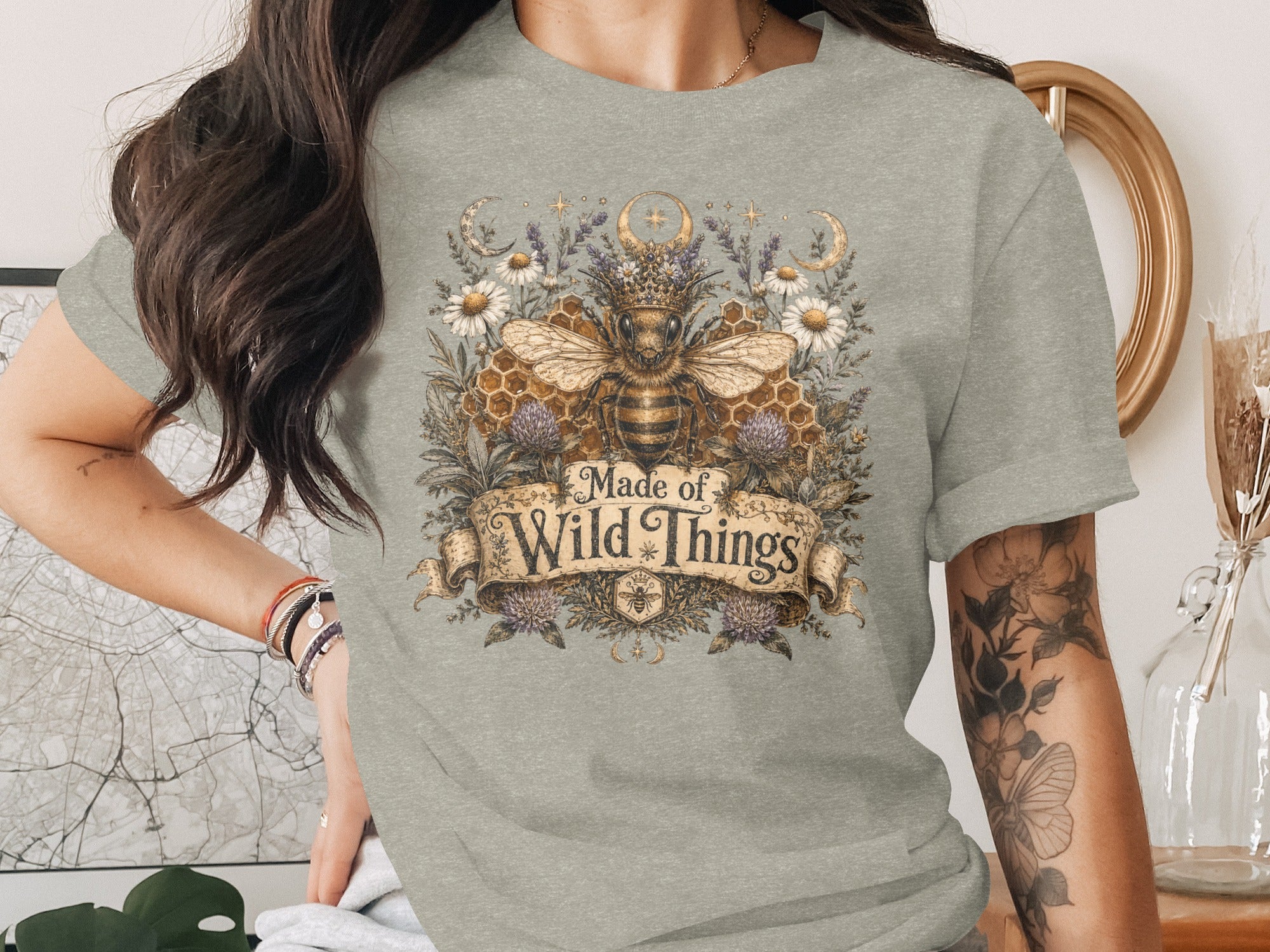 T-shirt with a regal bee, honeycomb, flowers, moons, and text "Made of Wild Things".