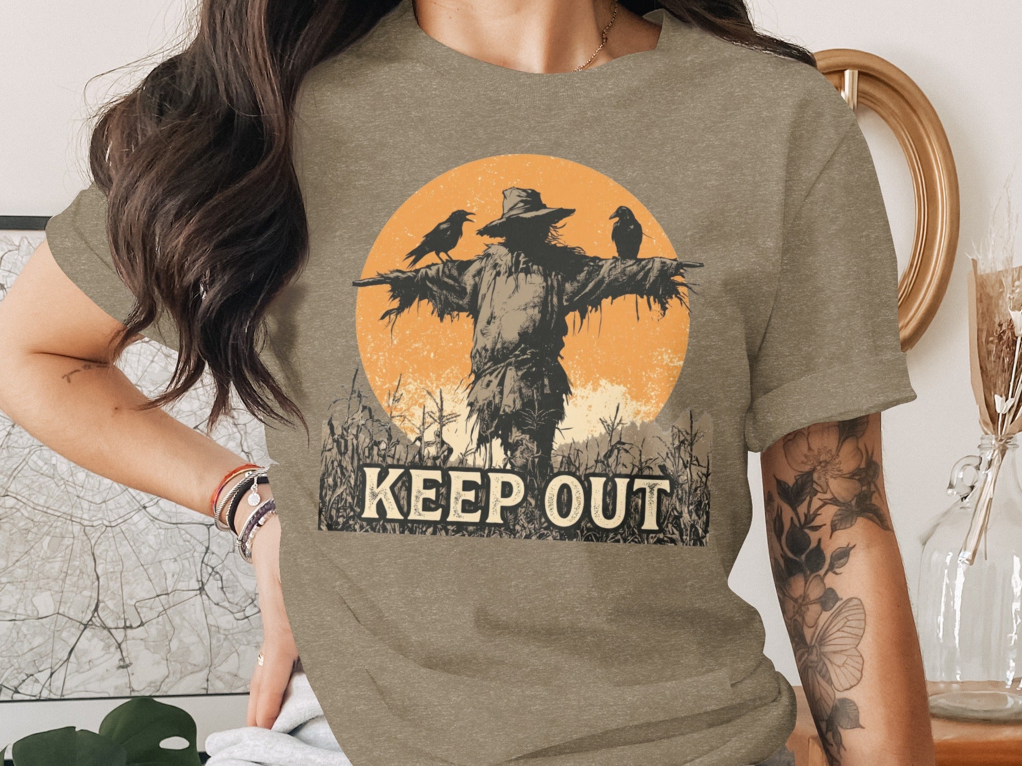 Scarecrow with two crows in cornfield with "KEEP OUT" text and orange sun.