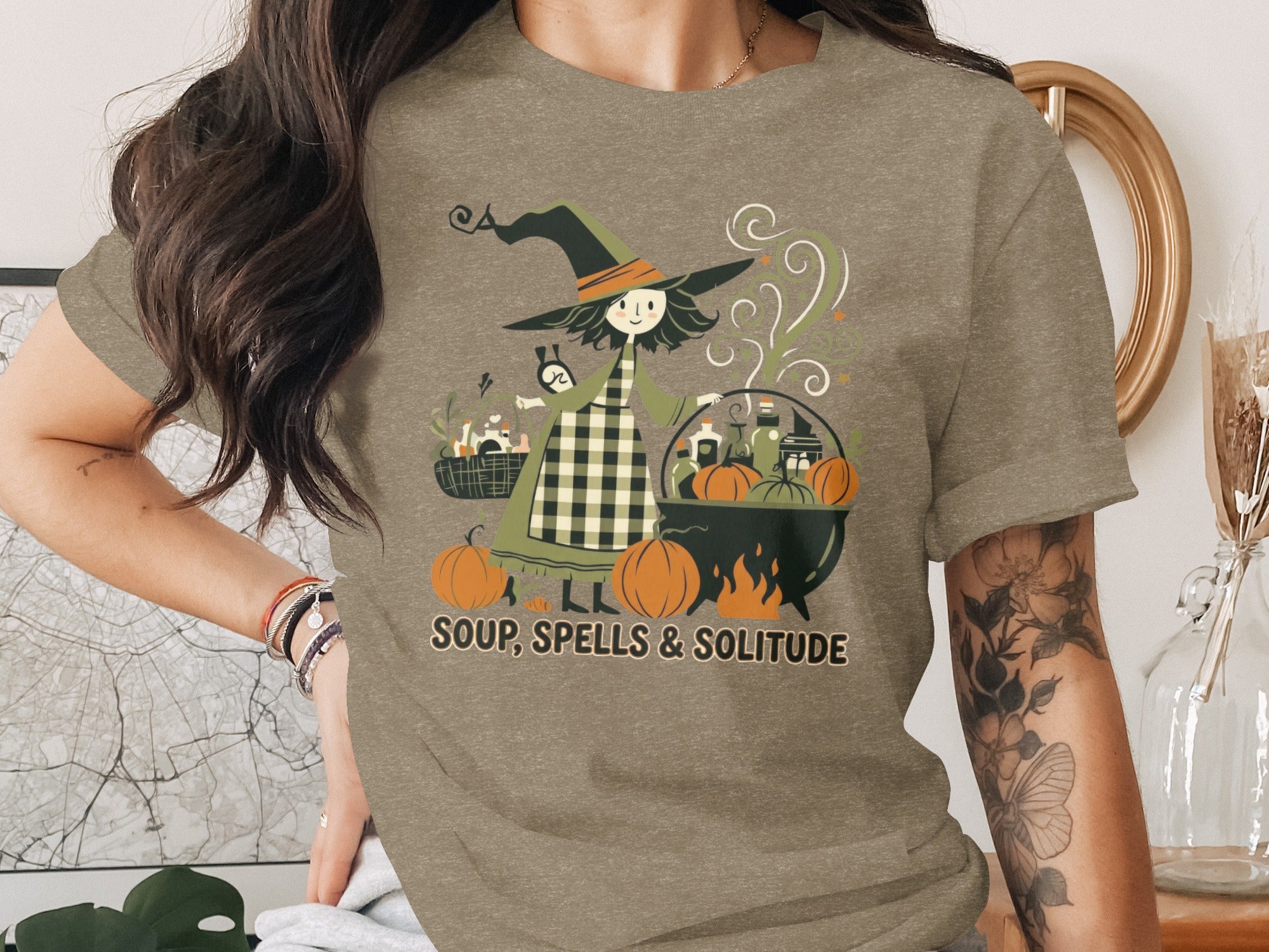 T-shirt graphic with witch, cauldron, pumpkins, and text "SOUP, SPELLS & SOLITUDE".