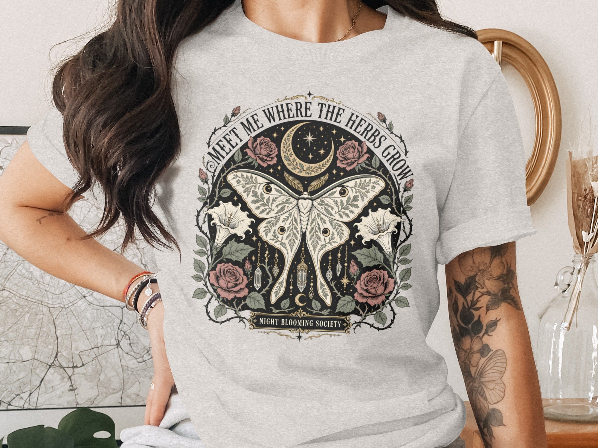 Grey t-shirt with "Meet Me Where The Herbs Grow" text, moon, stars, moth, roses, and crystals.