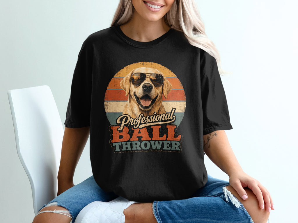 Black t-shirt with a retro graphic of a happy dog wearing sunglasses and the words "Professional BALL THROWER".