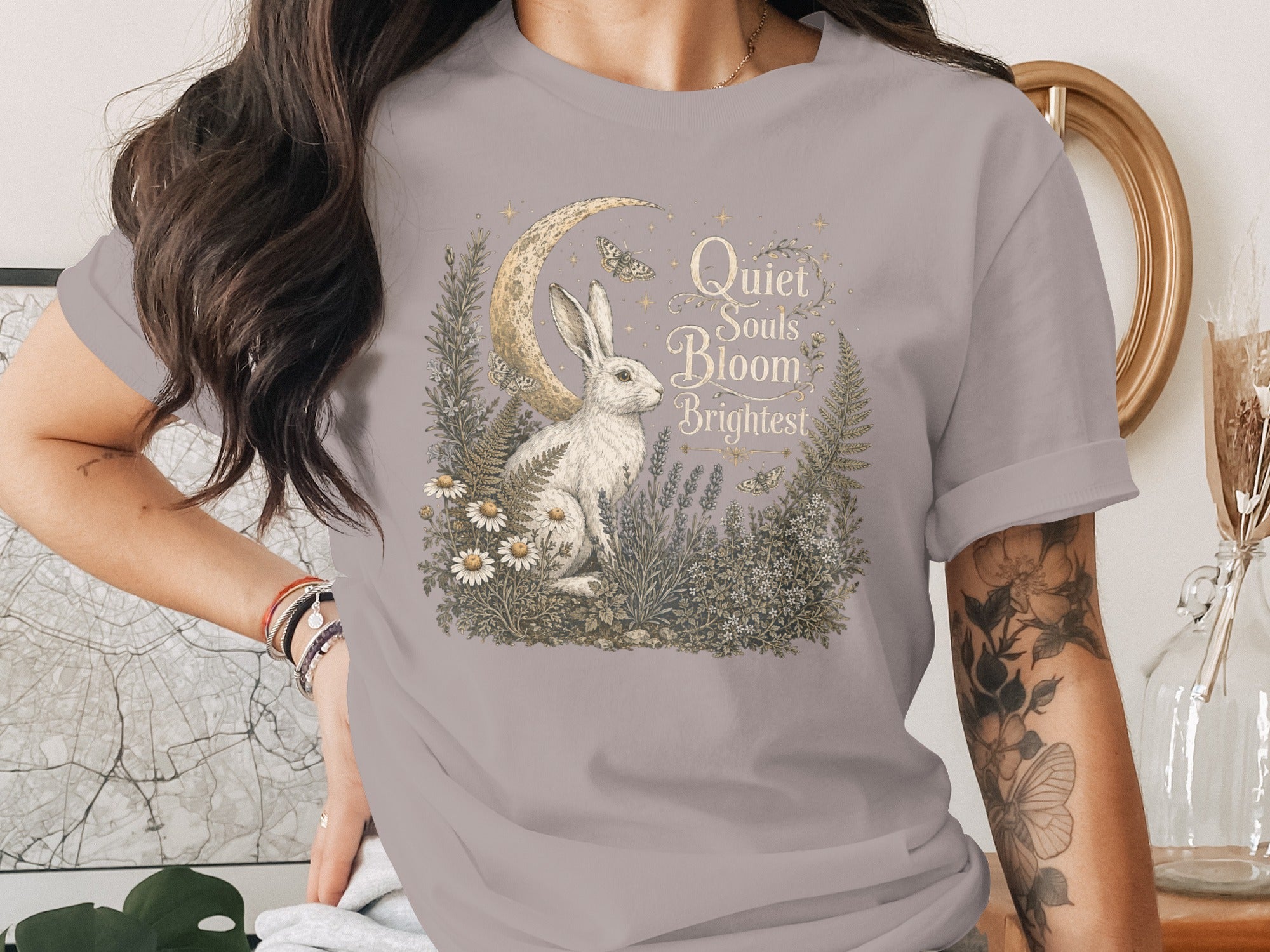 T-shirt featuring a white rabbit among moon, flora, and text "Quiet Souls Bloom Brightest".