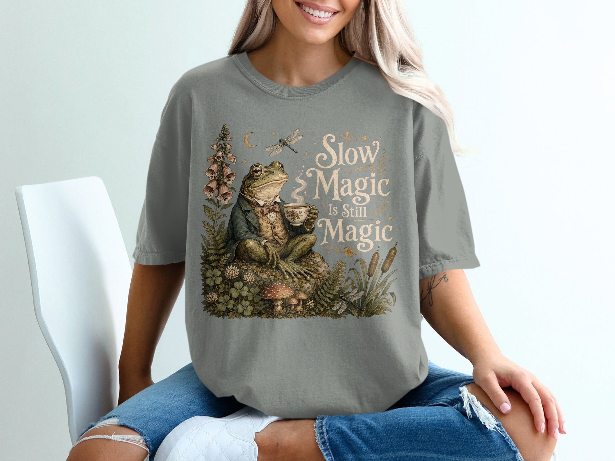 T-shirt graphic of a frog in a suit holding a teacup with text "Slow Magic Is Still Magic".