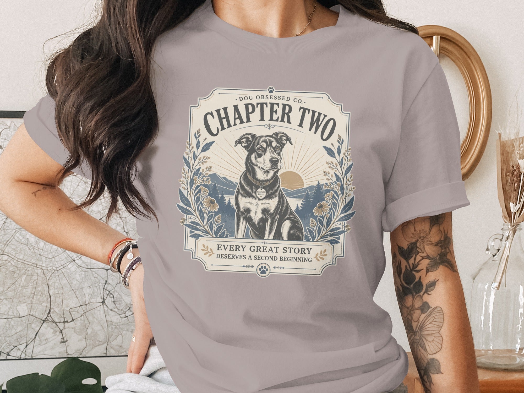 Grey t-shirt graphic with a dog, mountains, and text "CHAPTER TWO".