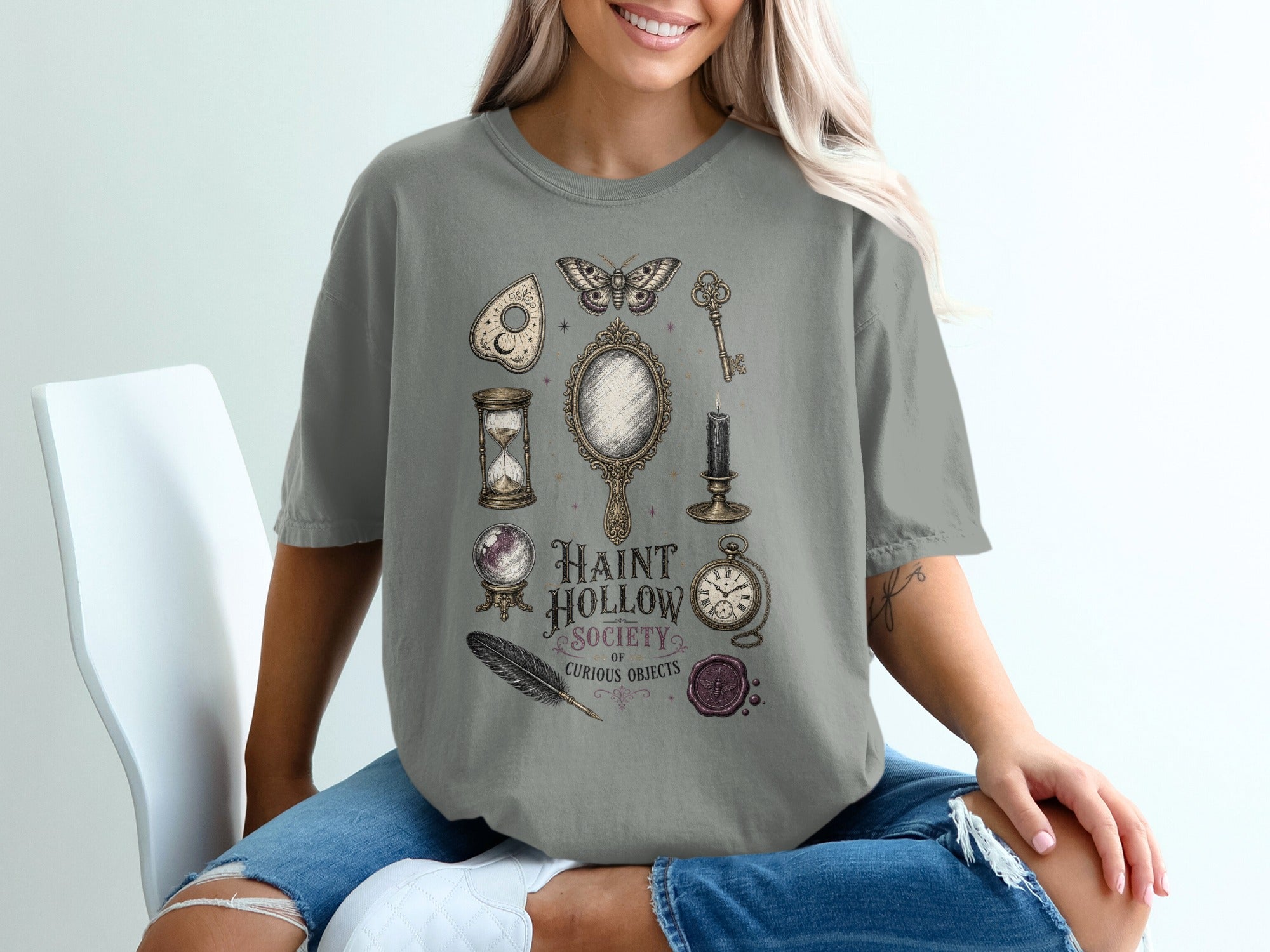 Gray t-shirt with Haunt Hollow Society of Curious Objects design featuring a moth, mirror, and vintage items.