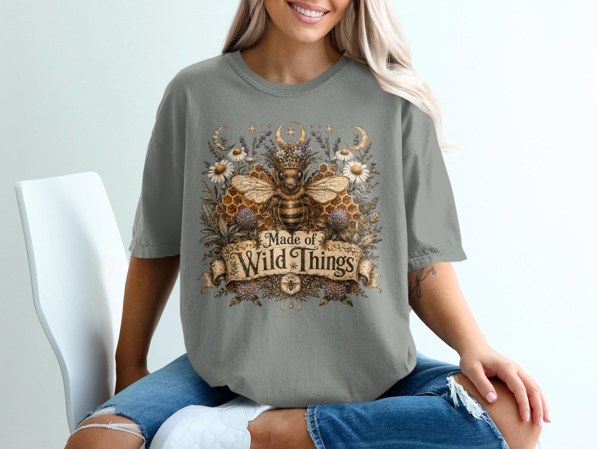 Gray t-shirt with a bee, flowers, moons, and text saying "Made of Wild Things".