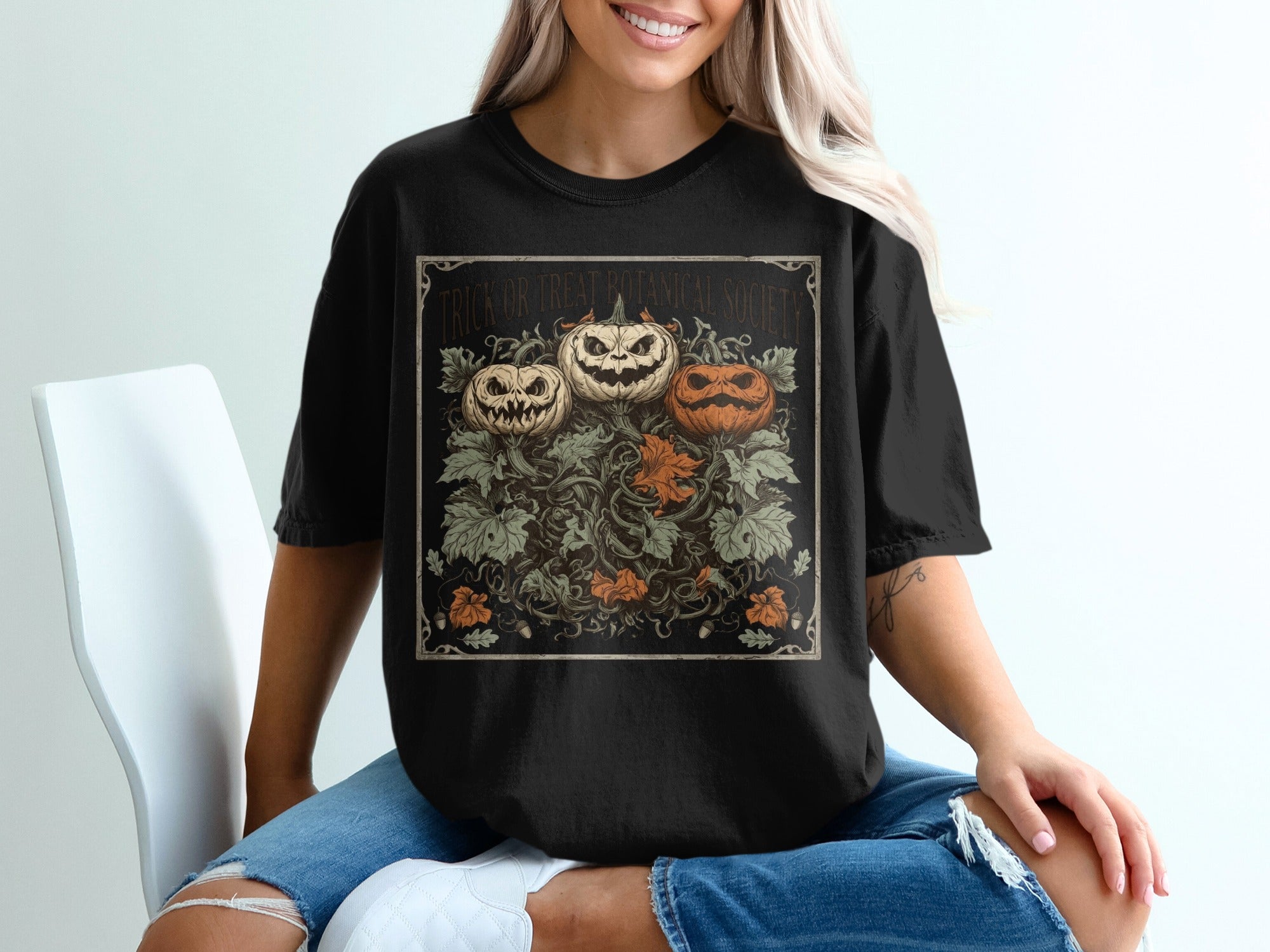 Black t-shirt with three carved pumpkins and botanicals, reading "Trick or Treat Botanical Society."