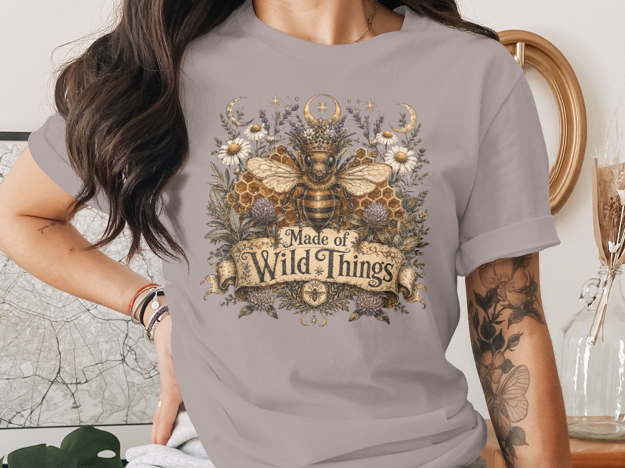 T-shirt with a regal bee, honeycomb, moon, stars, and flowers, and text "Made of Wild Things".