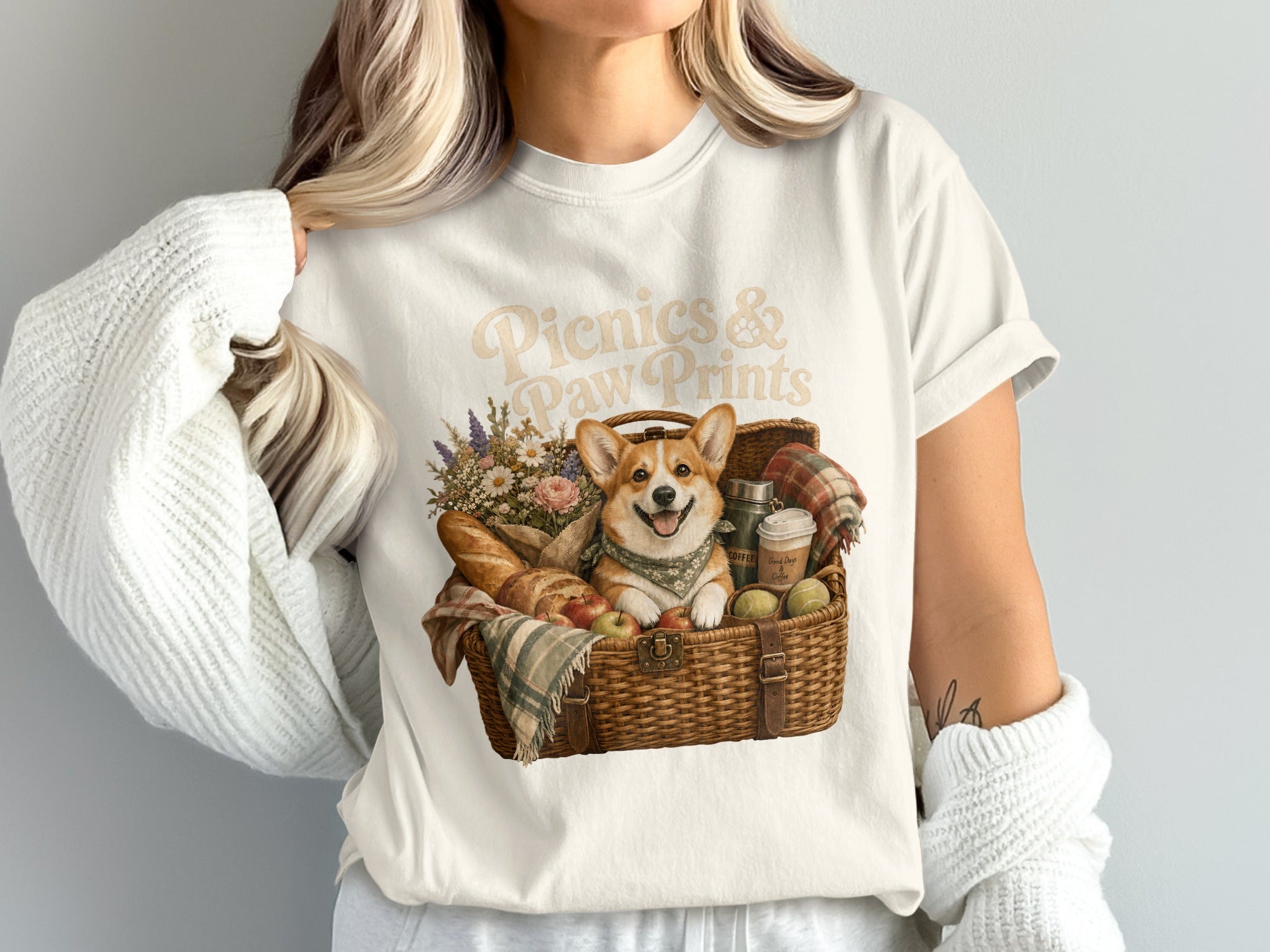 Picnics & Paw Prints text above corgi in picnic basket with bread and flowers.