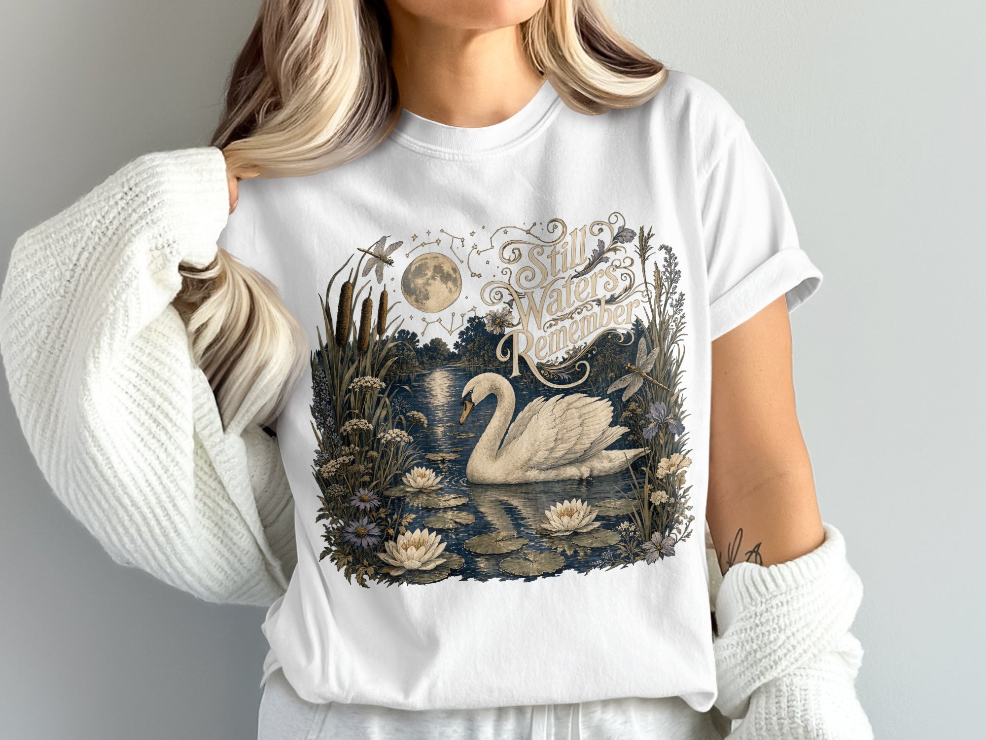 White t-shirt with vintage-style illustration of a swan on a pond with moon and text.