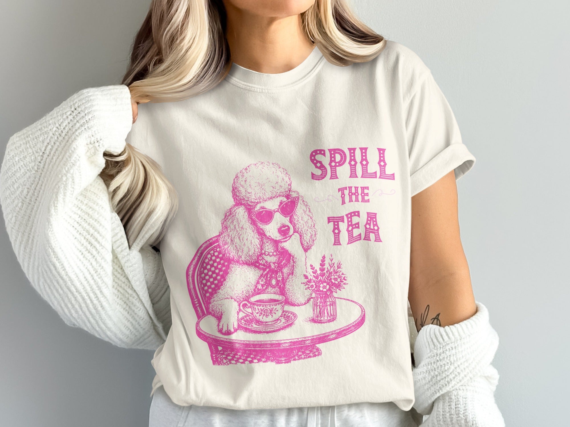 Pink poodle wearing sunglasses sits at a table drinking tea with "Spill the Tea" text.