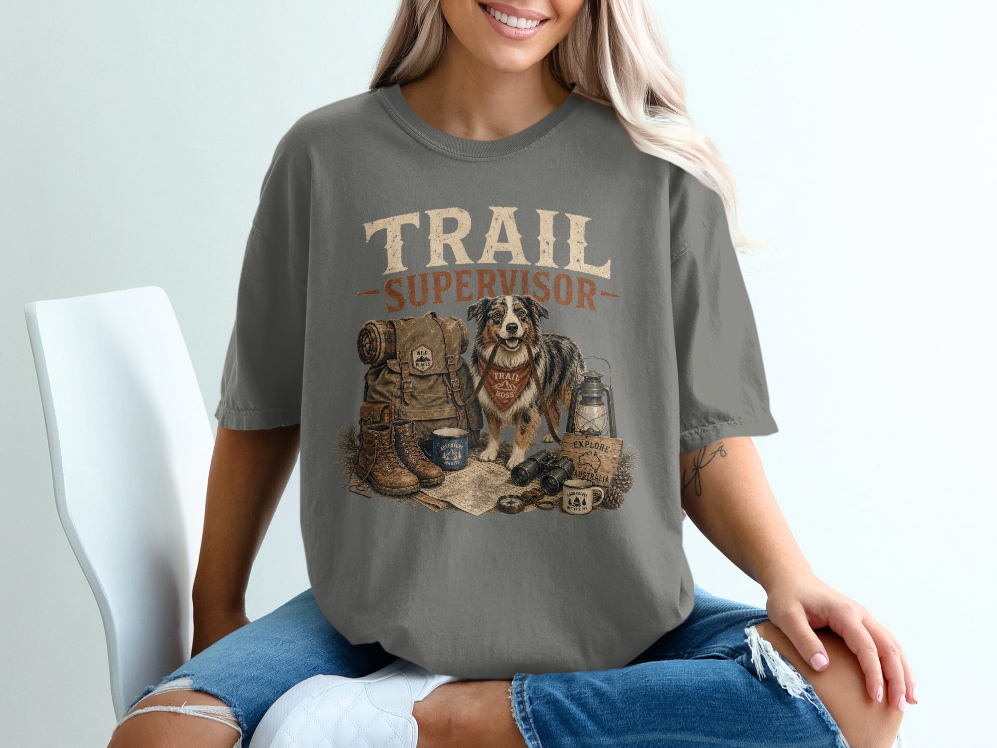 T-shirt with "TRAIL SUPERVISOR" text featuring dog, backpack, boots, map, and camping gear.
