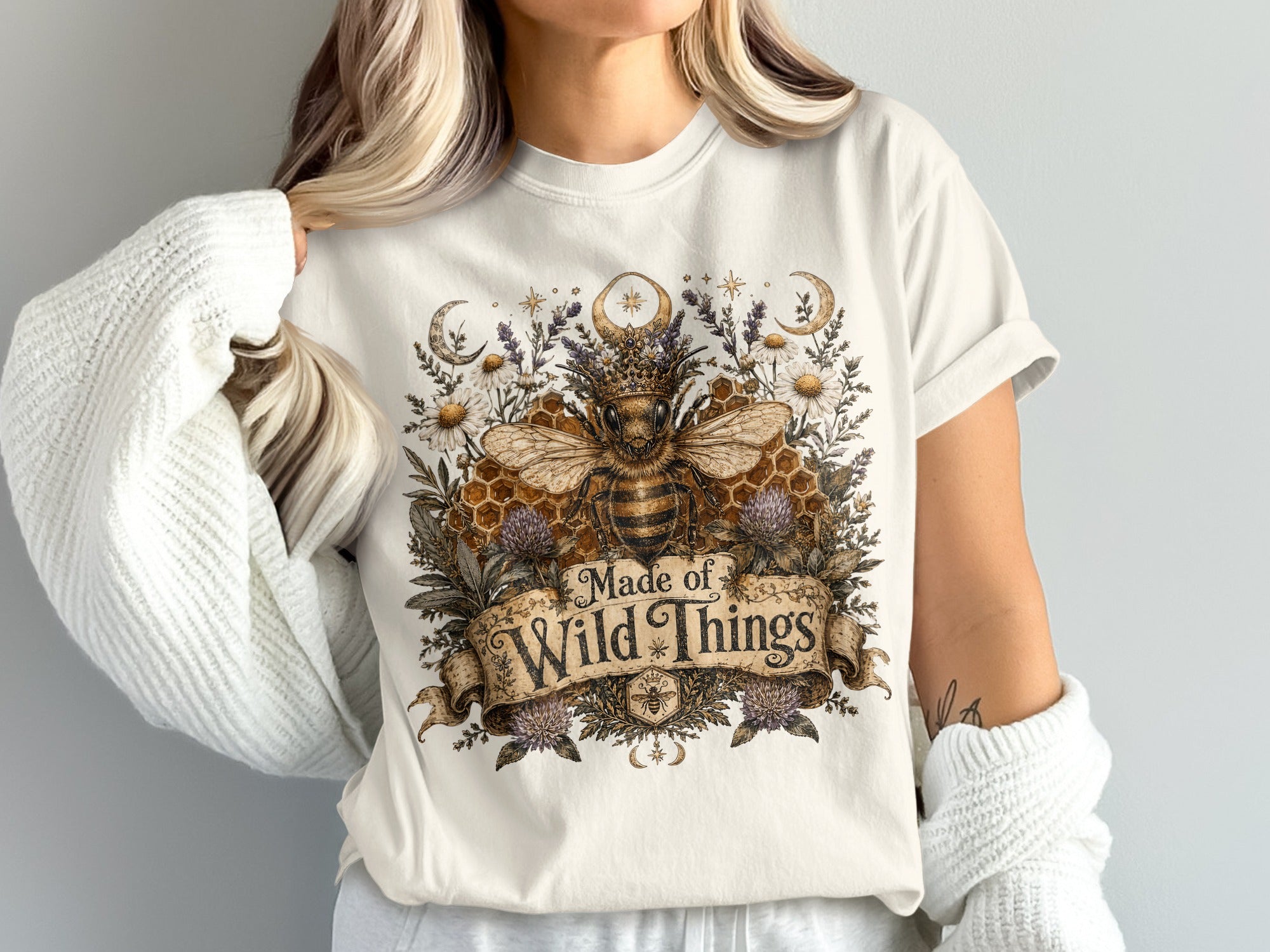 T-shirt with a royal bee wearing a crown, surrounded by flowers, moons, and the text "Made of Wild Things."