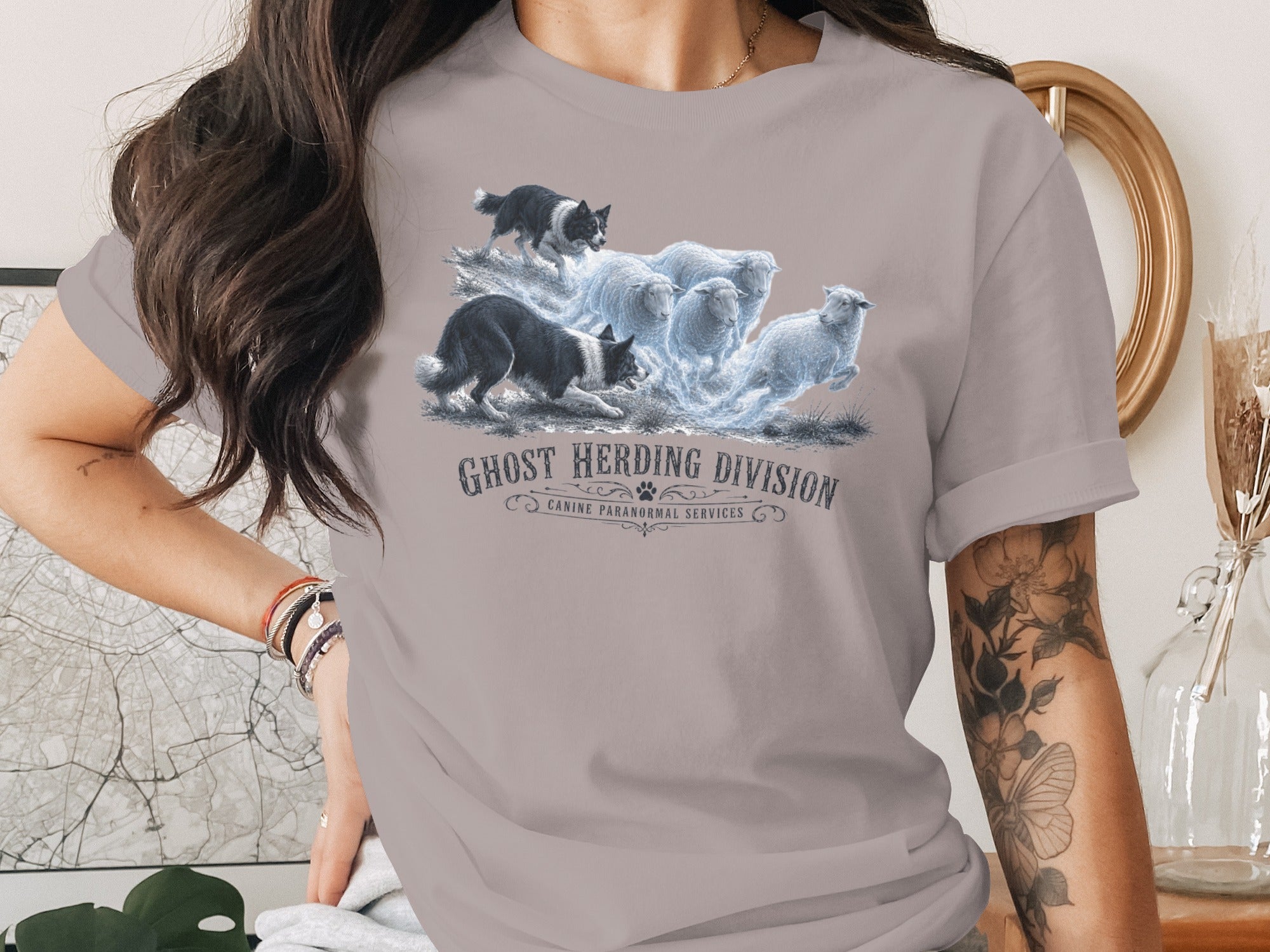 T-shirt graphic: Border collies herding glowing sheep below "GHOST HERDING DIVISION" text.