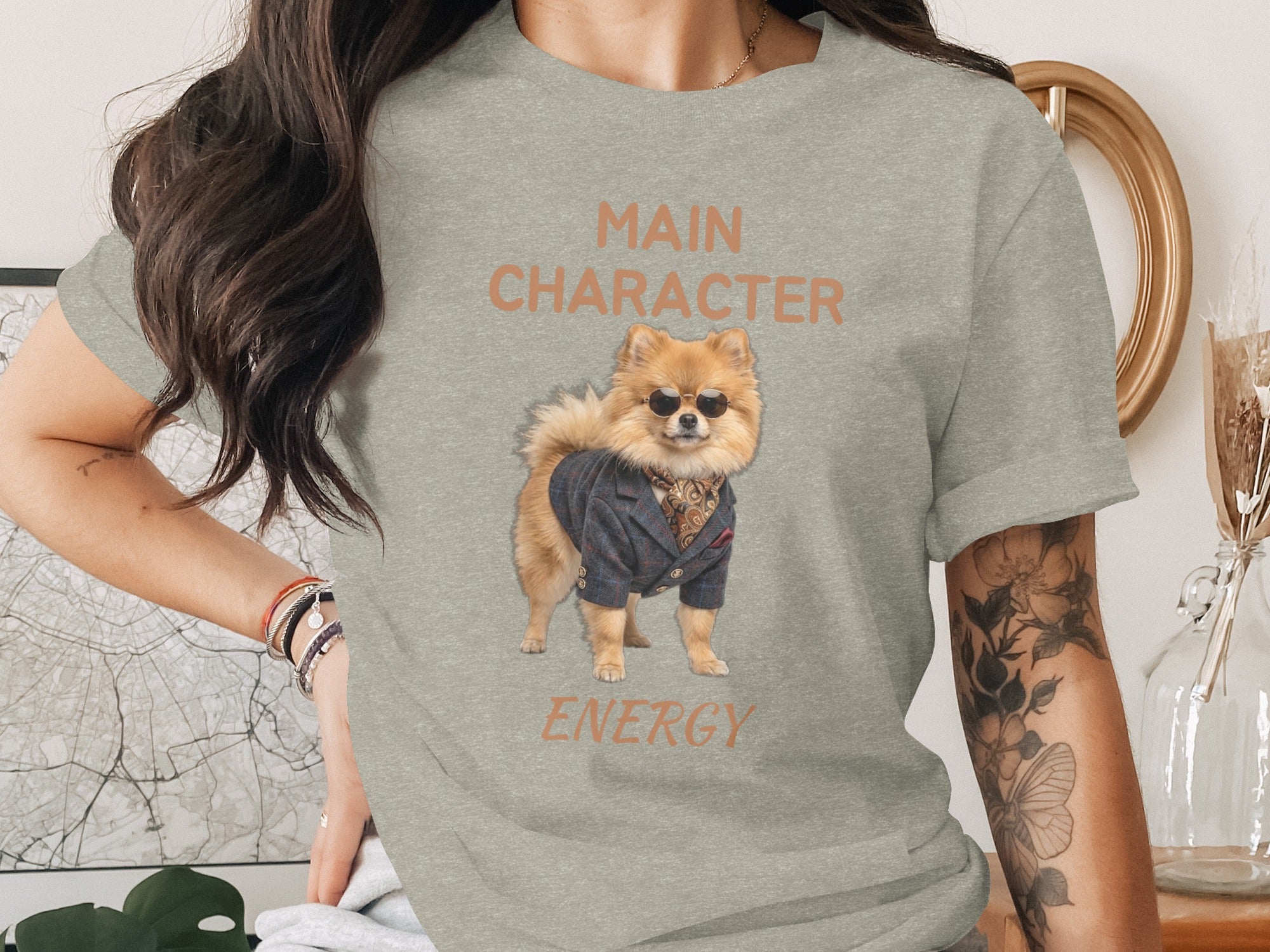 Grey t-shirt with a Pomeranian dog wearing sunglasses and a suit, text reads "MAIN CHARACTER ENERGY".