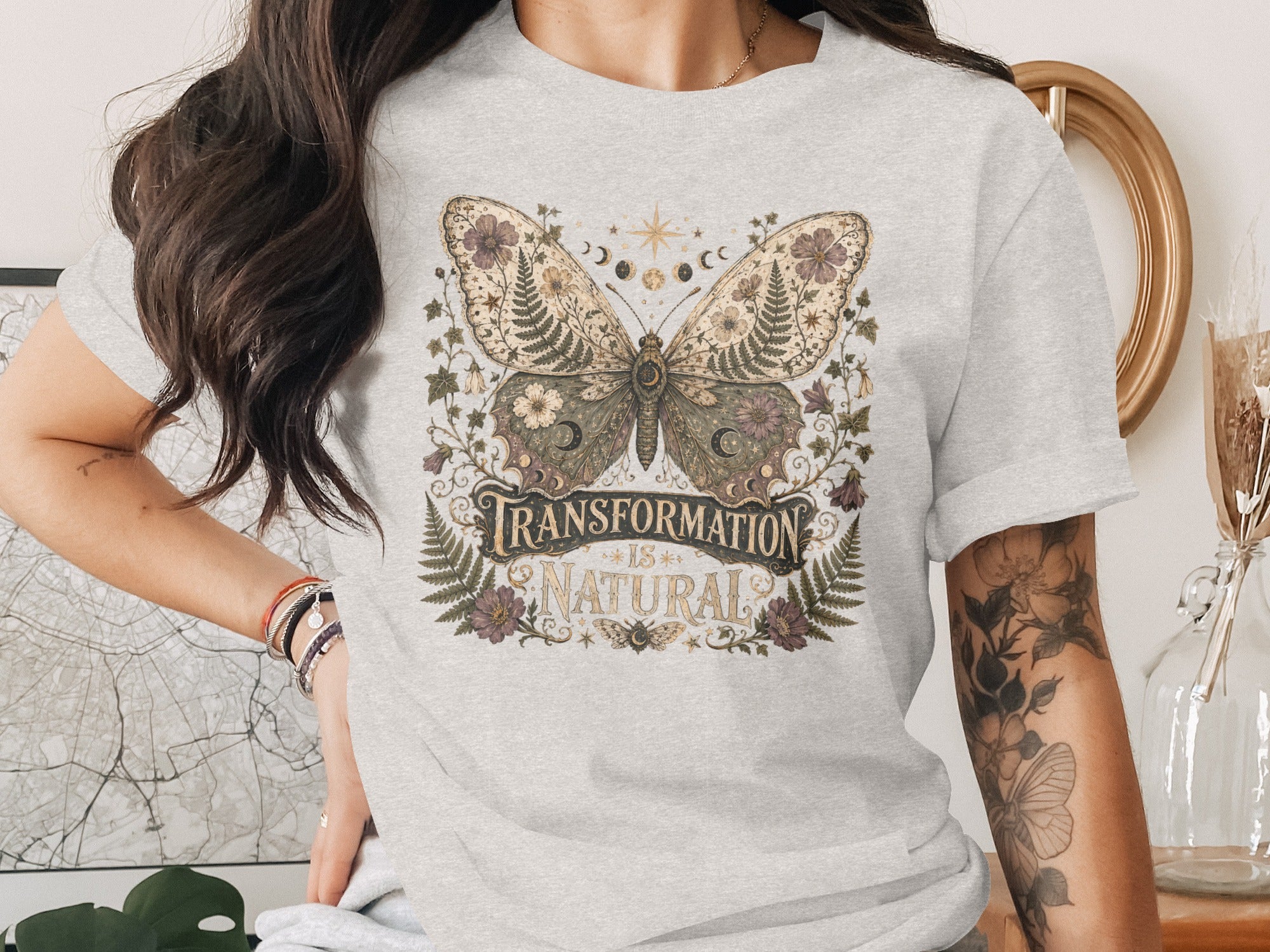 Light gray t-shirt with a butterfly and floral design, "Transformation is Natural" text.