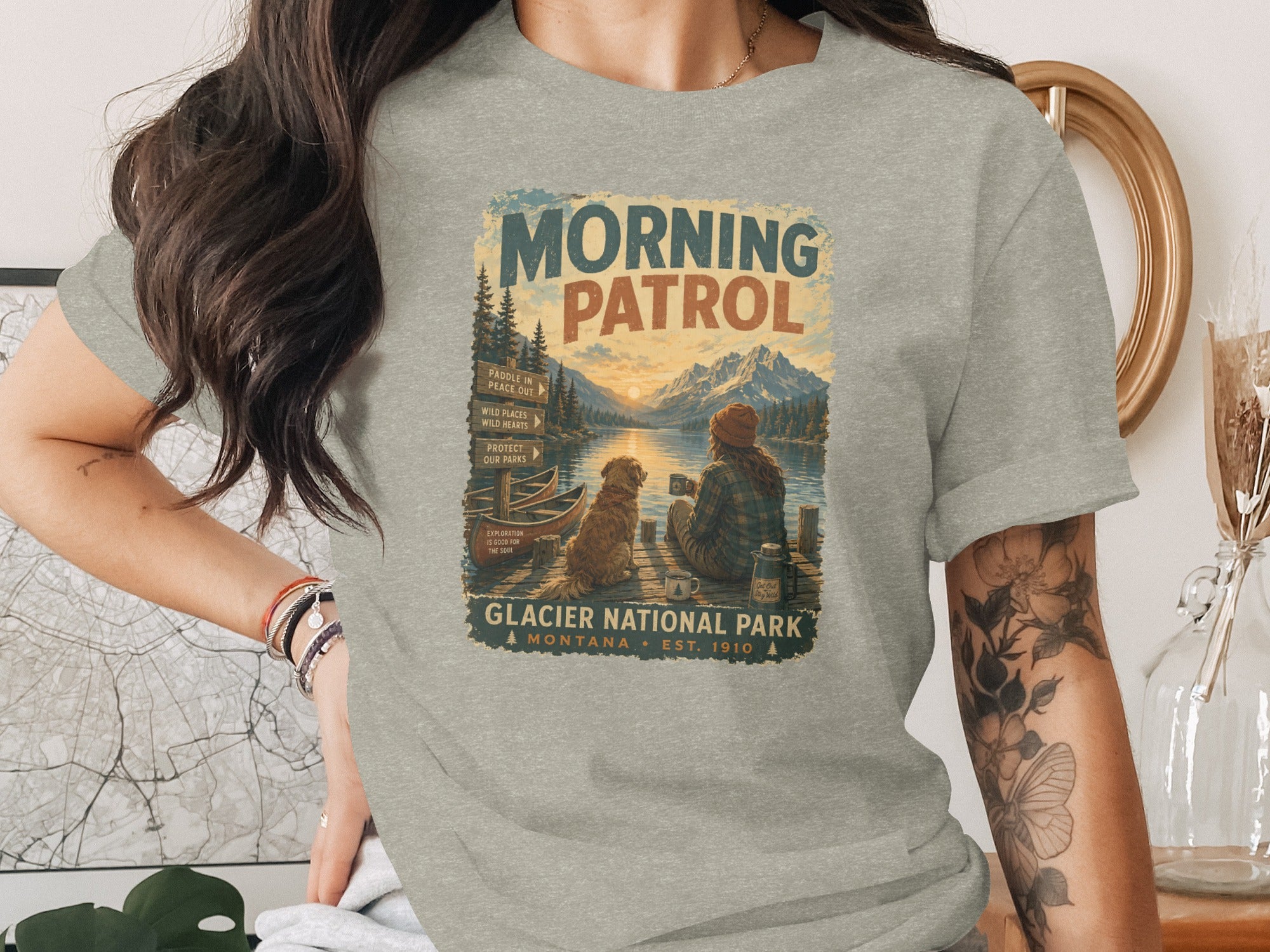 Glacier National Park "Morning Patrol" graphic with a person and dog on a dock at sunrise.