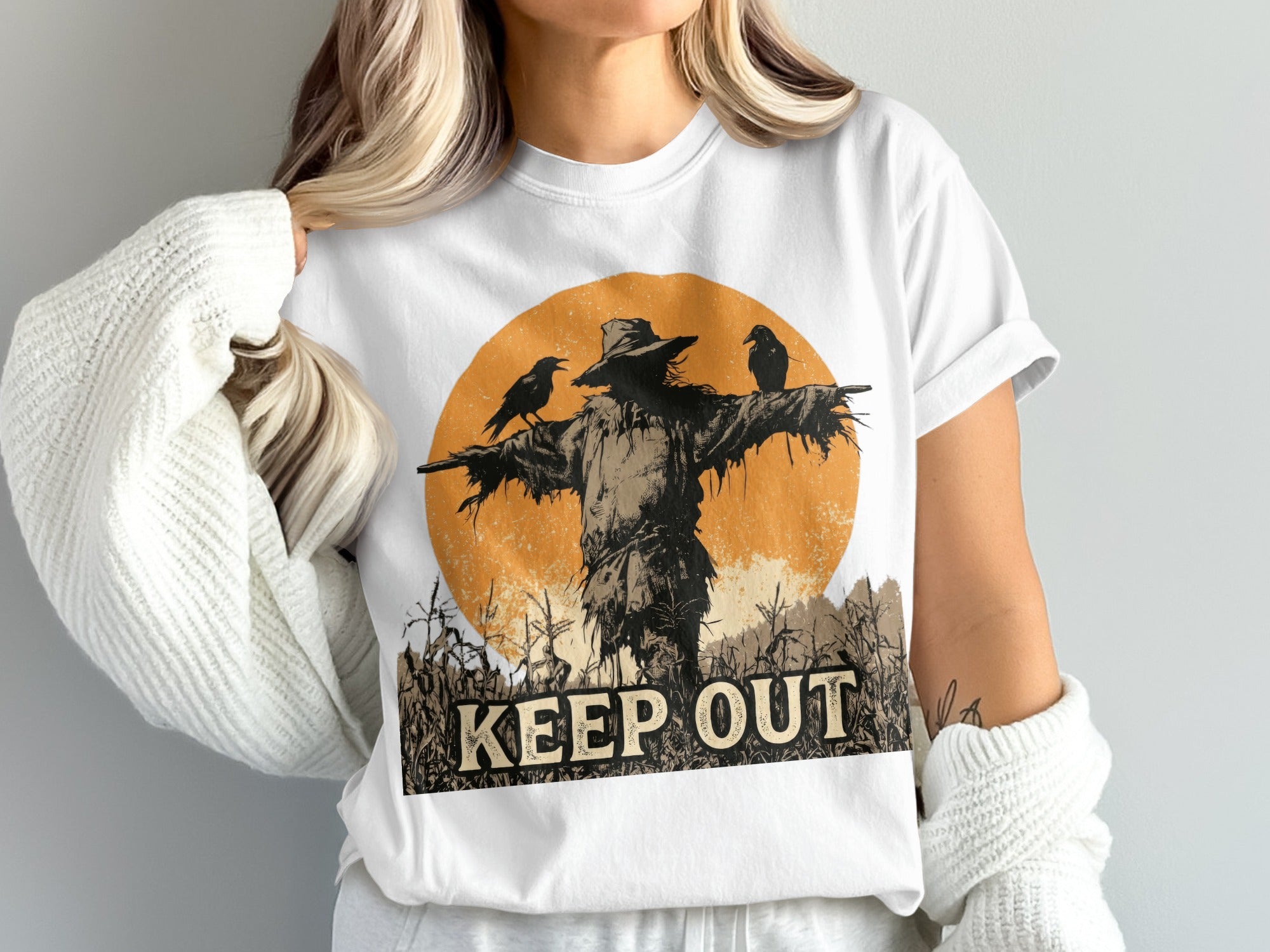 White t-shirt with a scarecrow, two crows, and cornfield design, saying "KEEP OUT".