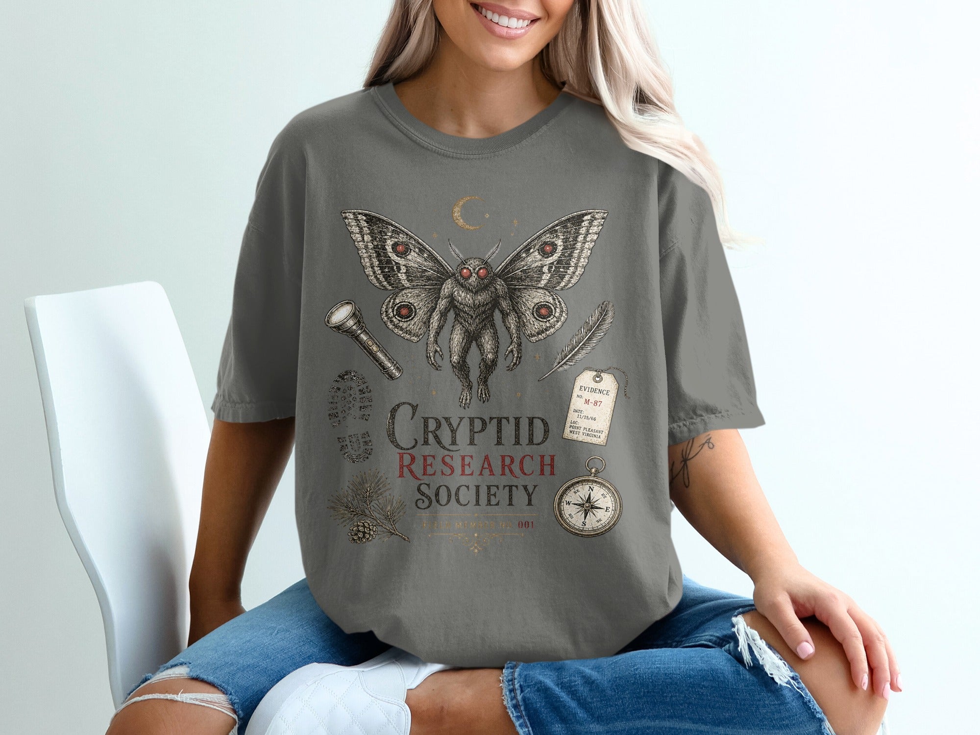 Mothman and cryptid research society graphic on a dark gray t-shirt.