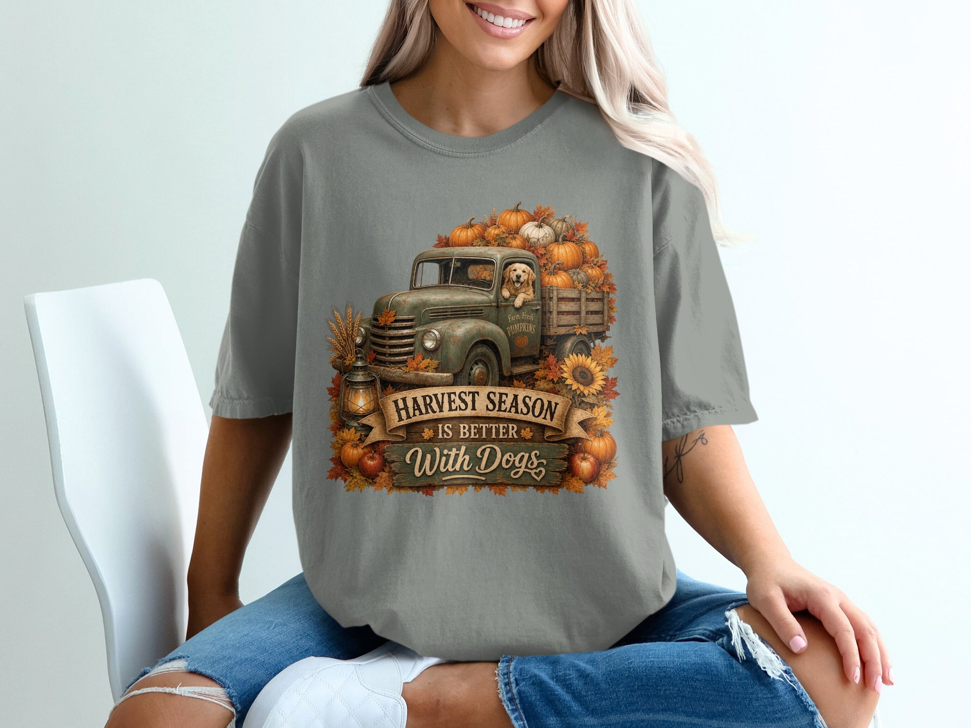 Grey t-shirt graphic with vintage truck, golden retriever, pumpkins, and text "Harvest Season is Better With Dogs".