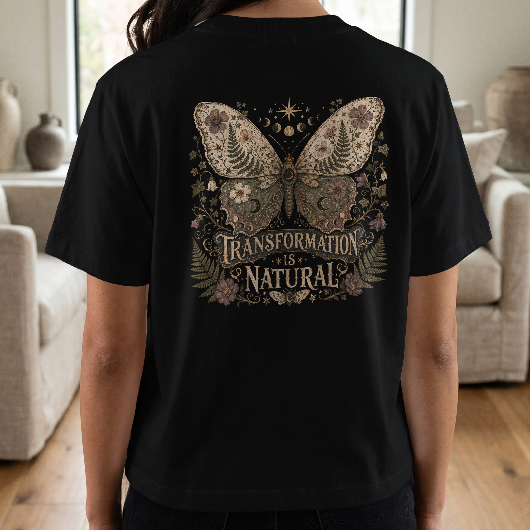 Black t-shirt with a celestial butterfly graphic and text "Transformation is Natural."