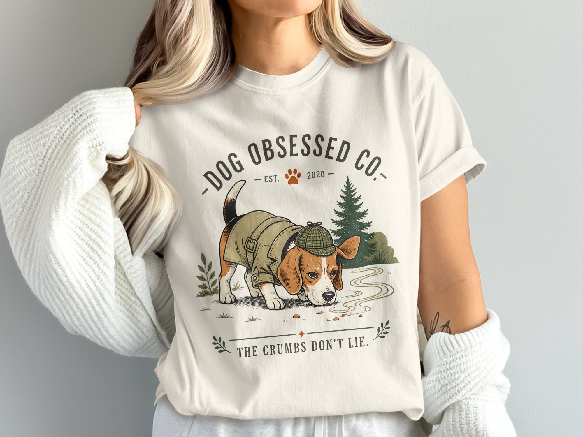 Beagle dog in trench coat and hat, with text "DOG OBSESSED CO. EST. 2020" and "THE CRUMBS DON'T LIE."
