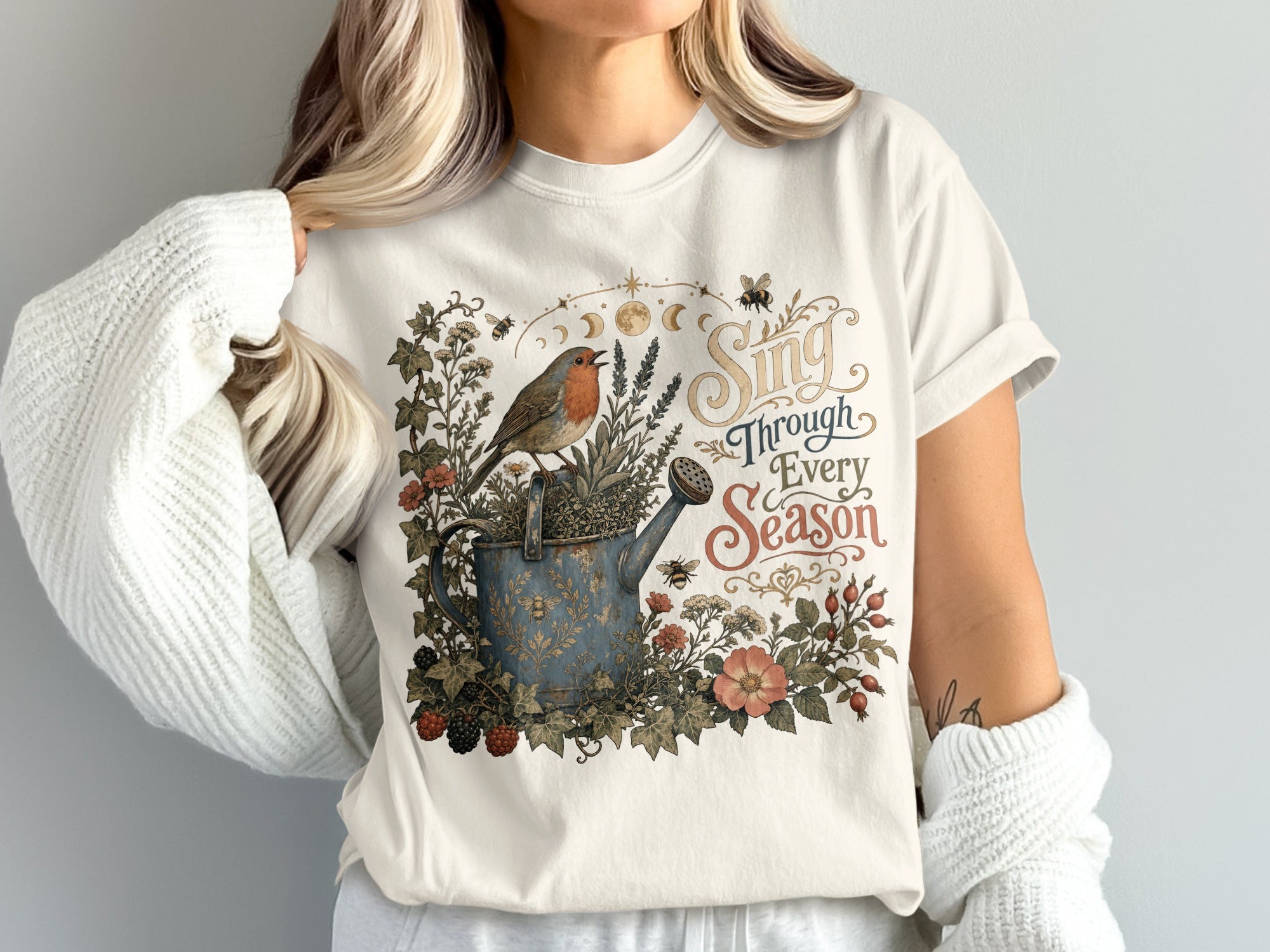 Robin on a watering can with flowers, bees and "Sing Through Every Season" text.