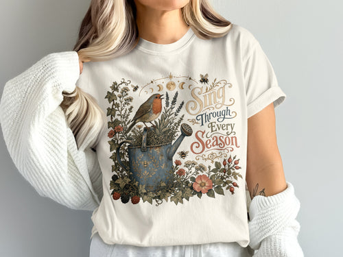 Robin on a watering can with flowers, bees and "Sing Through Every Season" text.
