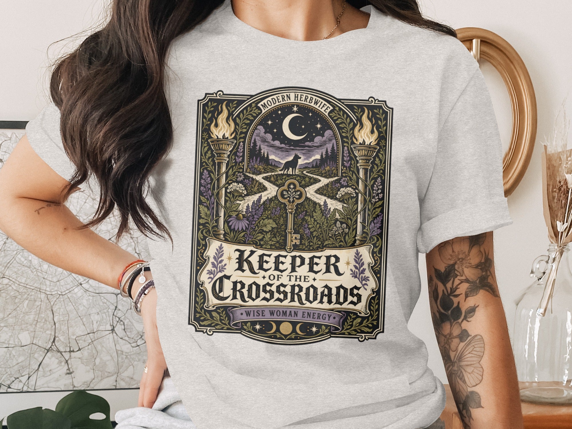 Grey t-shirt featuring "Keeper of the Crossroads" with a nocturnal wolf and a key.