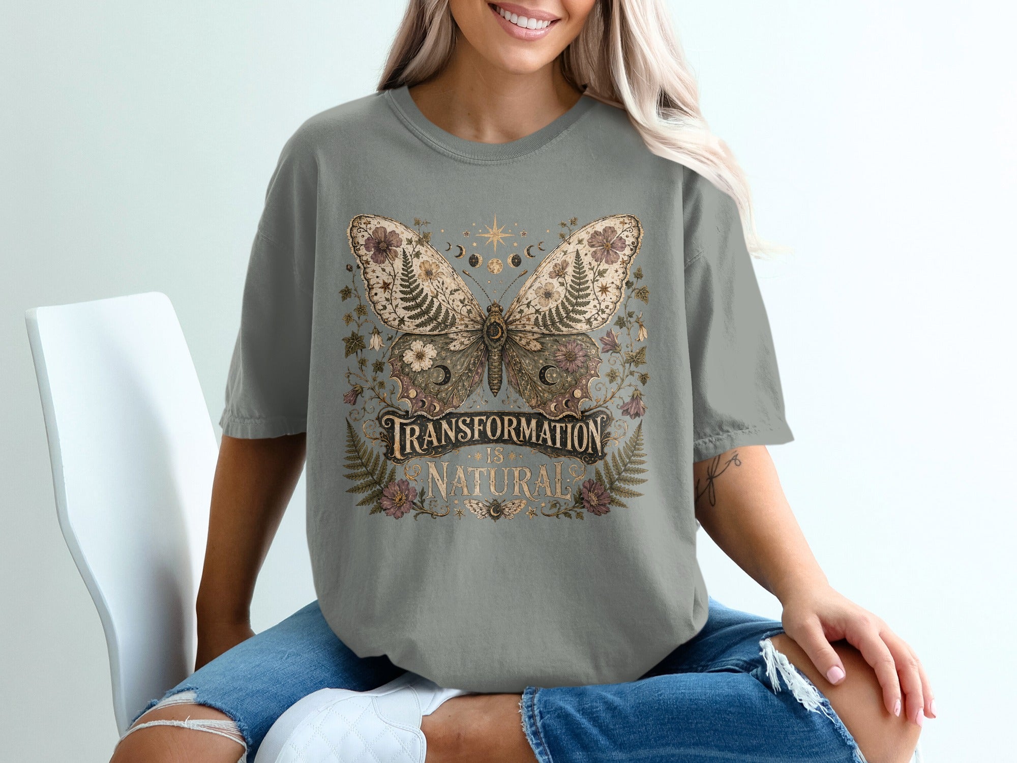 Grey t-shirt with a butterfly graphic featuring text "Transformation is Natural".