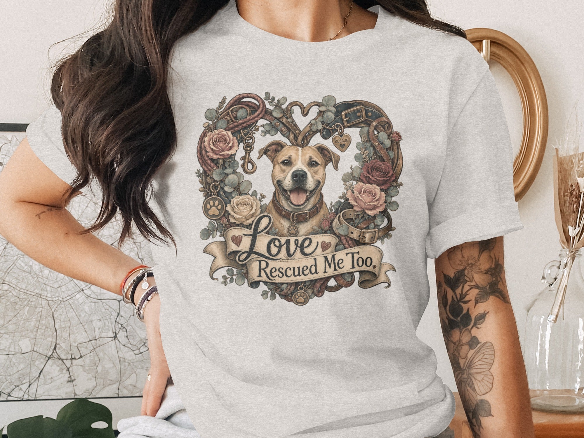 T-shirt graphic of a dog surrounded by flowers, rope, and collars, reading "Love Rescued Me Too."
