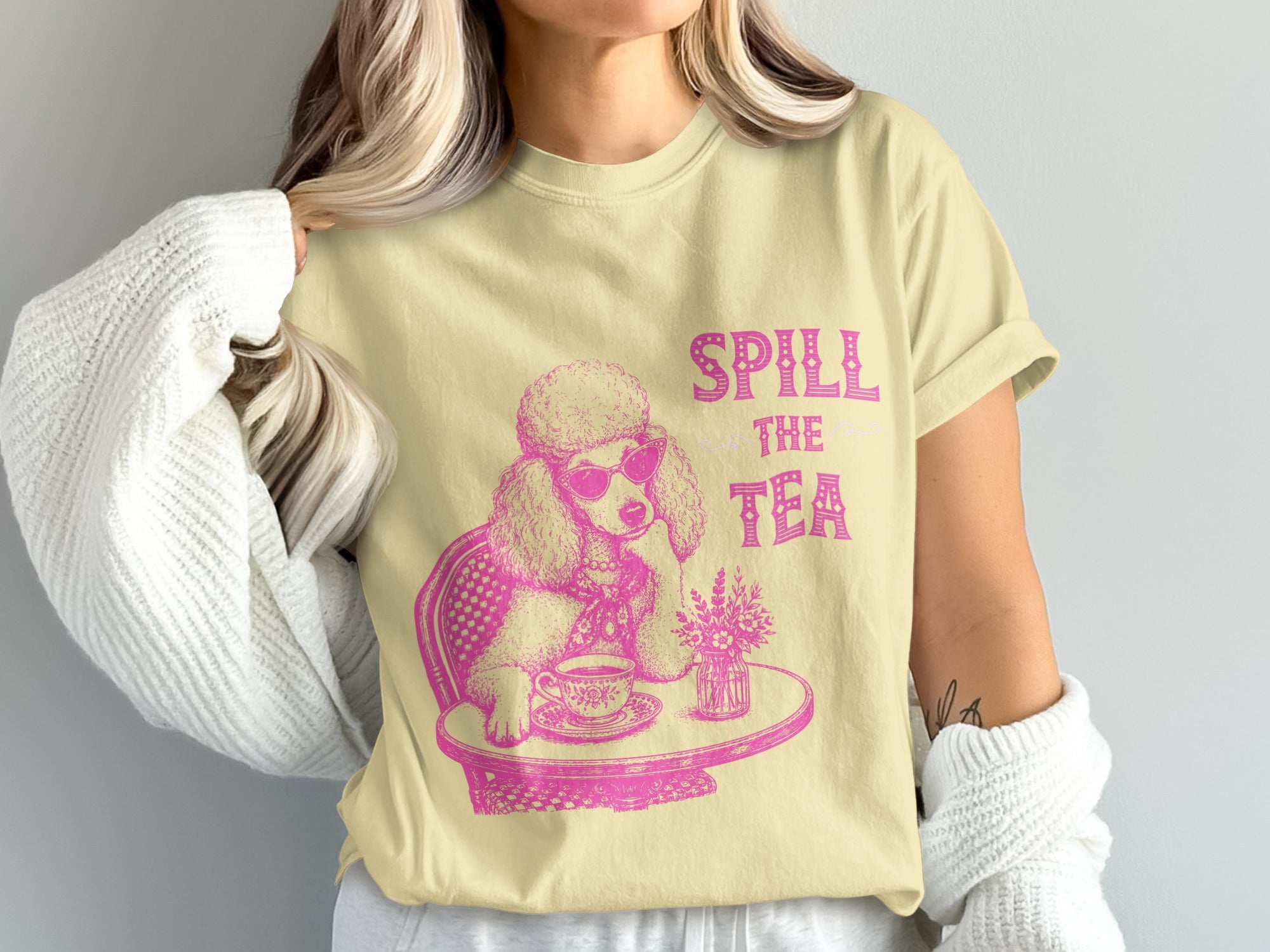 Yellow t-shirt with a pink graphic of a poodle wearing sunglasses, drinking tea. "SPILL THE TEA" text.