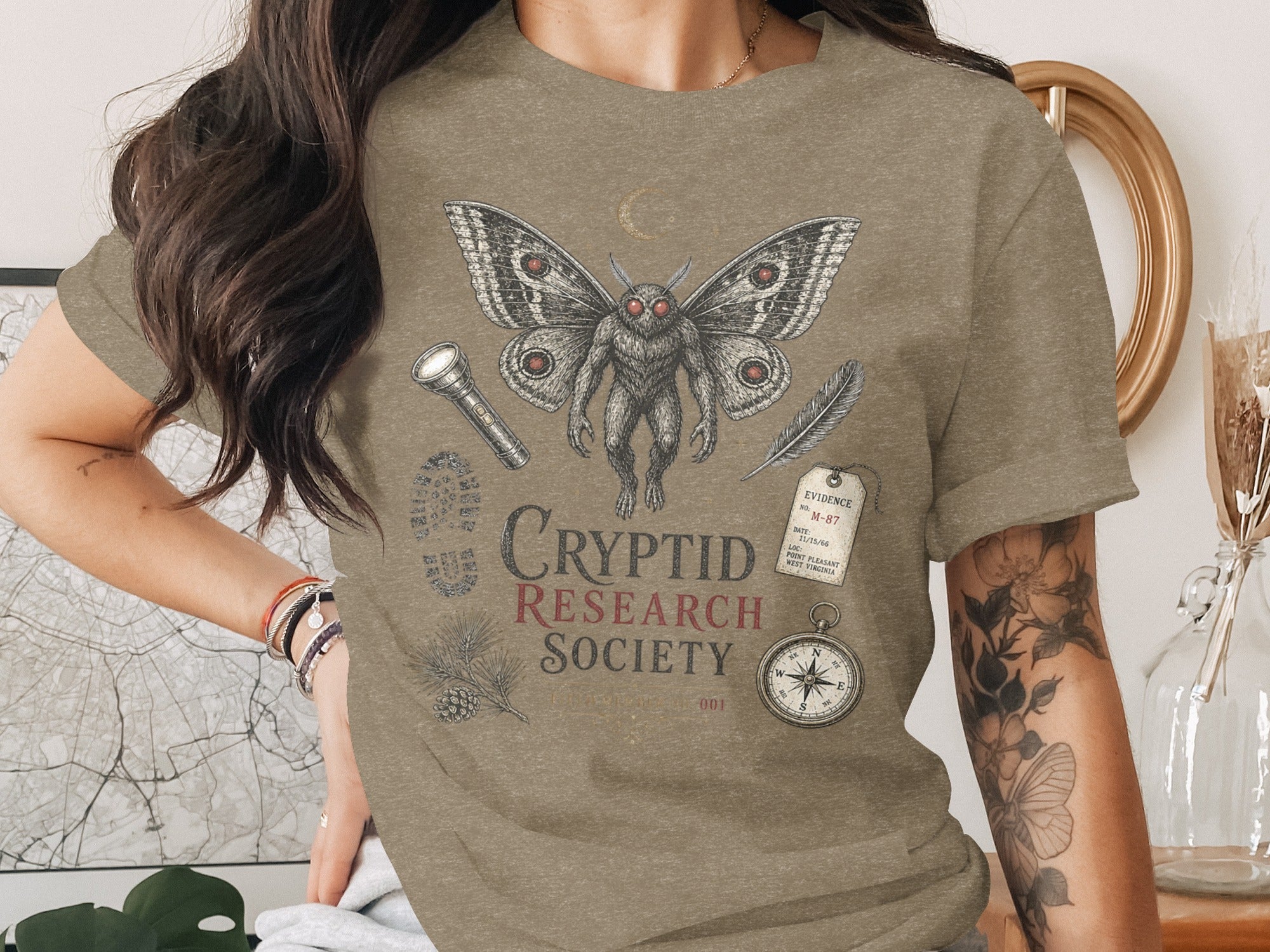 T-shirt with a mothman graphic, compass, and "Cryptid Research Society" text.