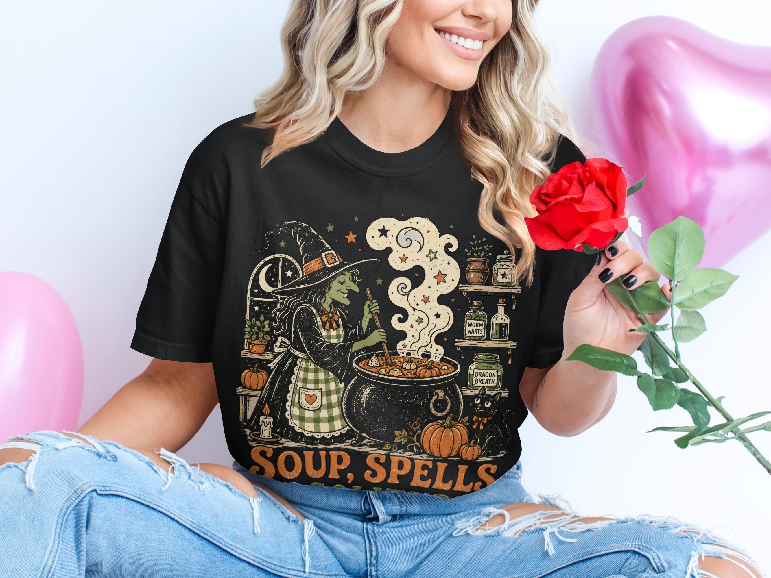 Black t-shirt with illustration of witch brewing soup, text says "Soup, Spells".