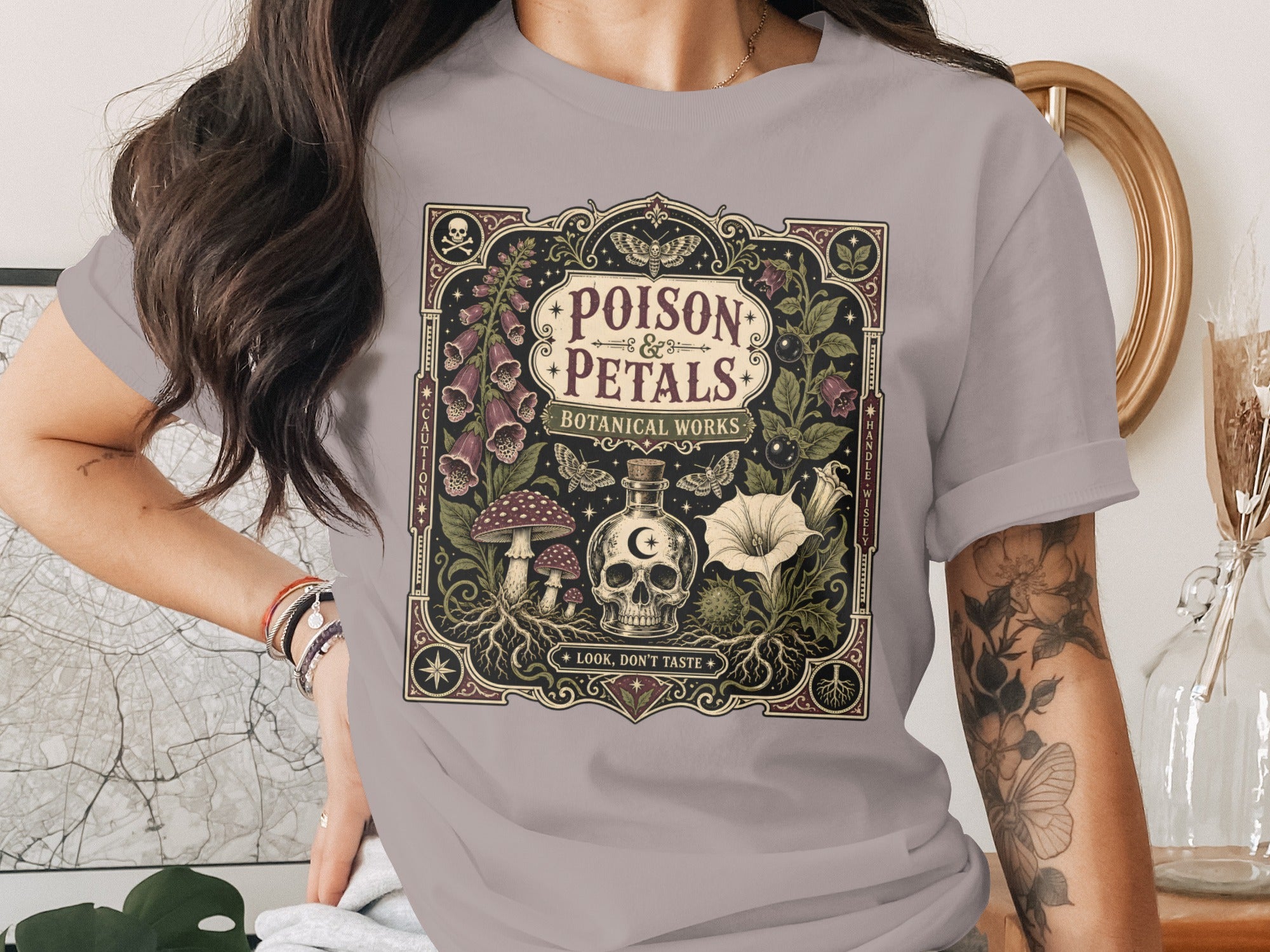"Poison & Petals Botanical Works" graphic on a gray t-shirt.
