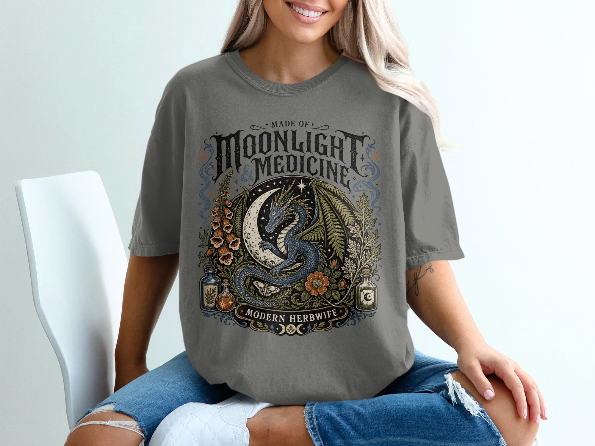 Grey t-shirt with a circular graphic featuring a blue dragon, moon, plants, and text.