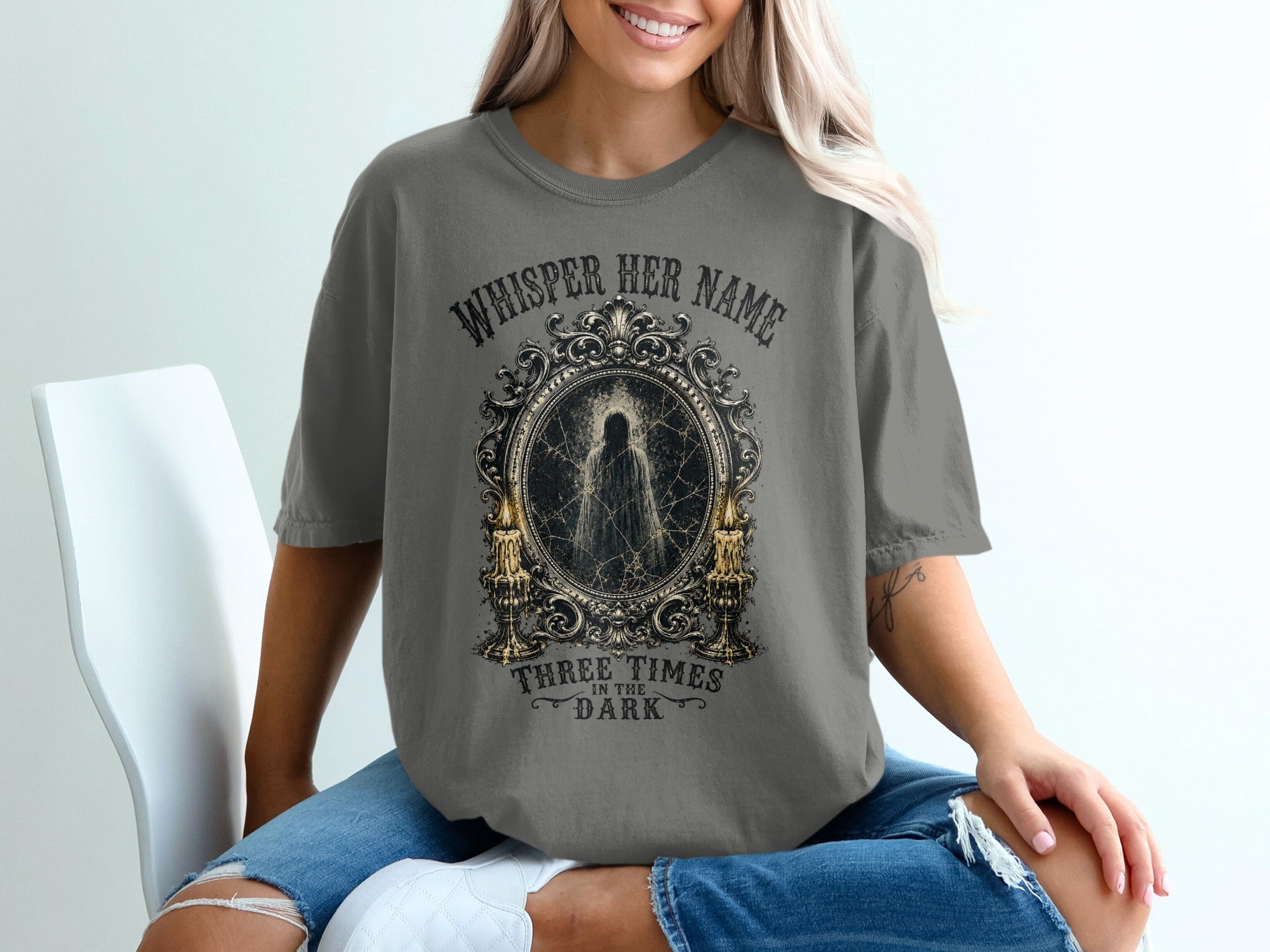 Gray t-shirt with gothic graphics: "Whisper Her Name" and a ghost in a mirror.