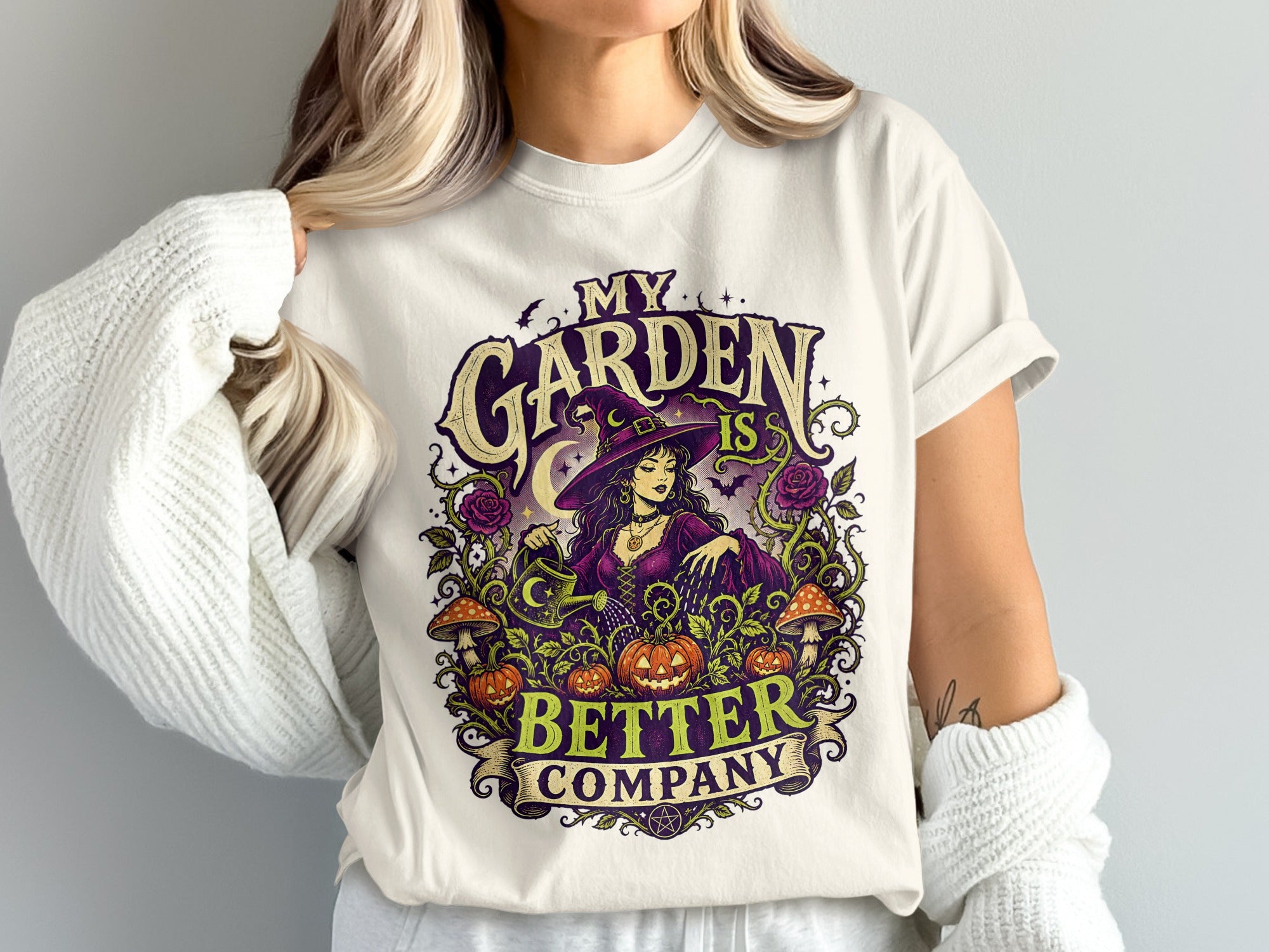 T-shirt with "My Garden Is Better Company" graphic featuring a witch watering pumpkins.