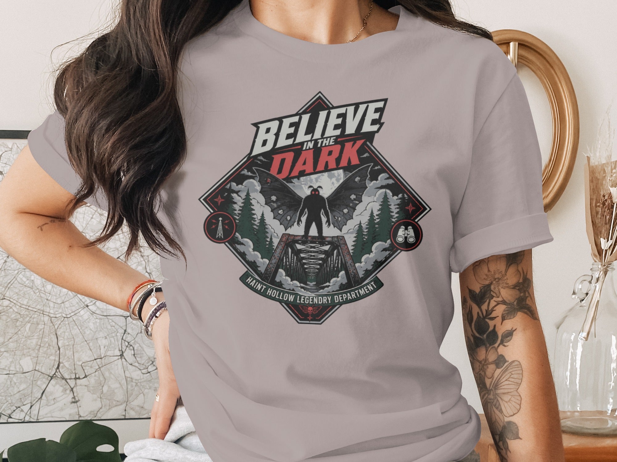 "Believe in the Dark" graphic tee with mothman on a bridge and text.