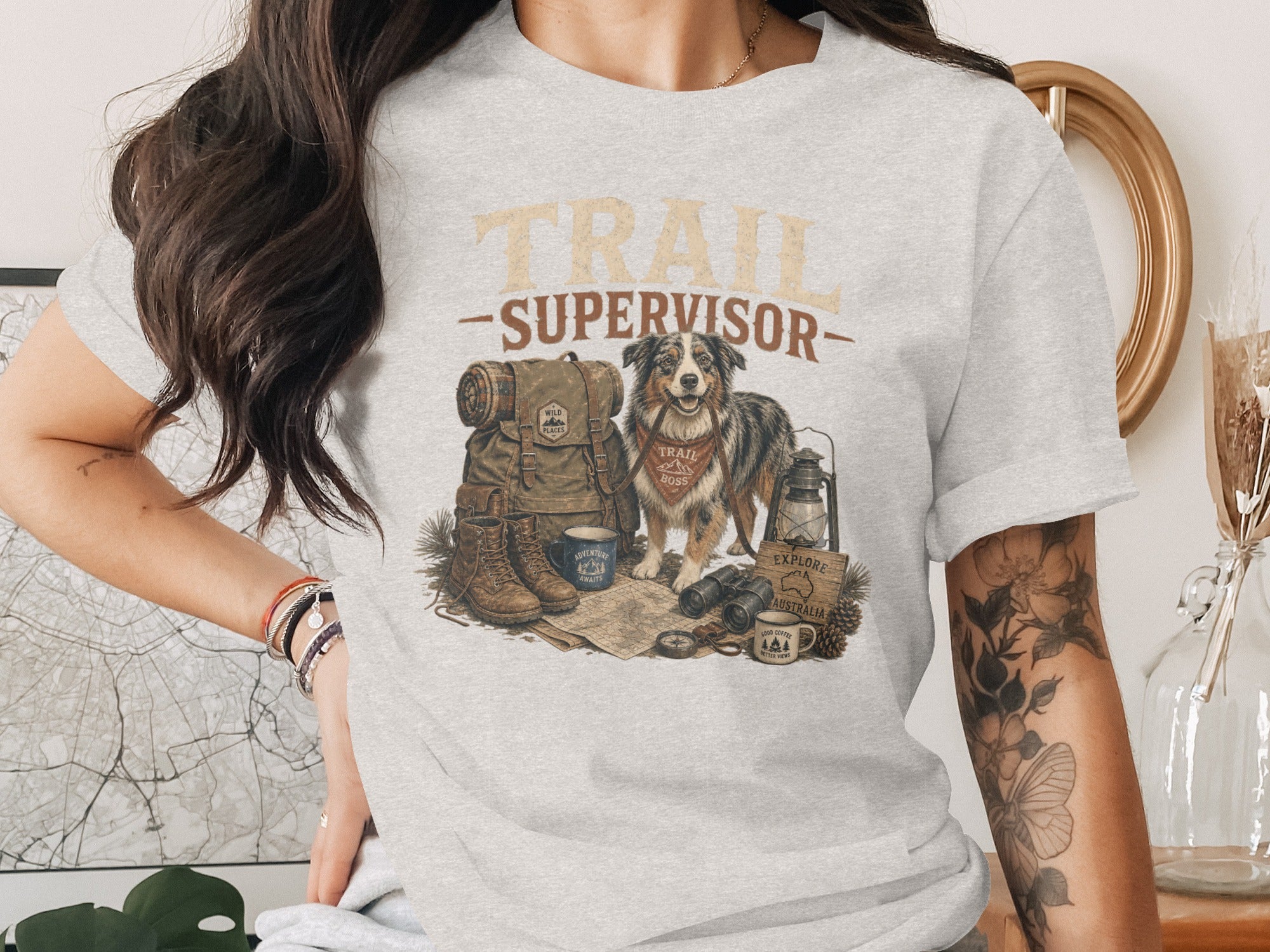 "TRAIL SUPERVISOR" text above dog, backpack, boots, and camping gear.