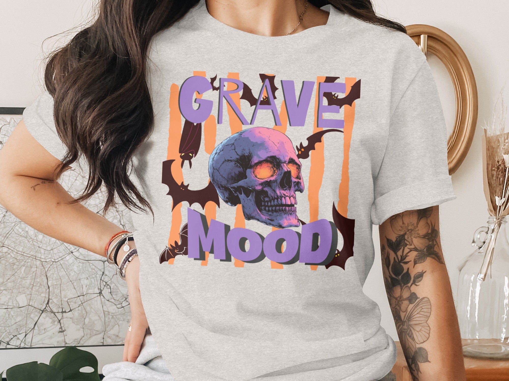 "Grave Mood" text graphic on a light gray t-shirt featuring a skull and bats.